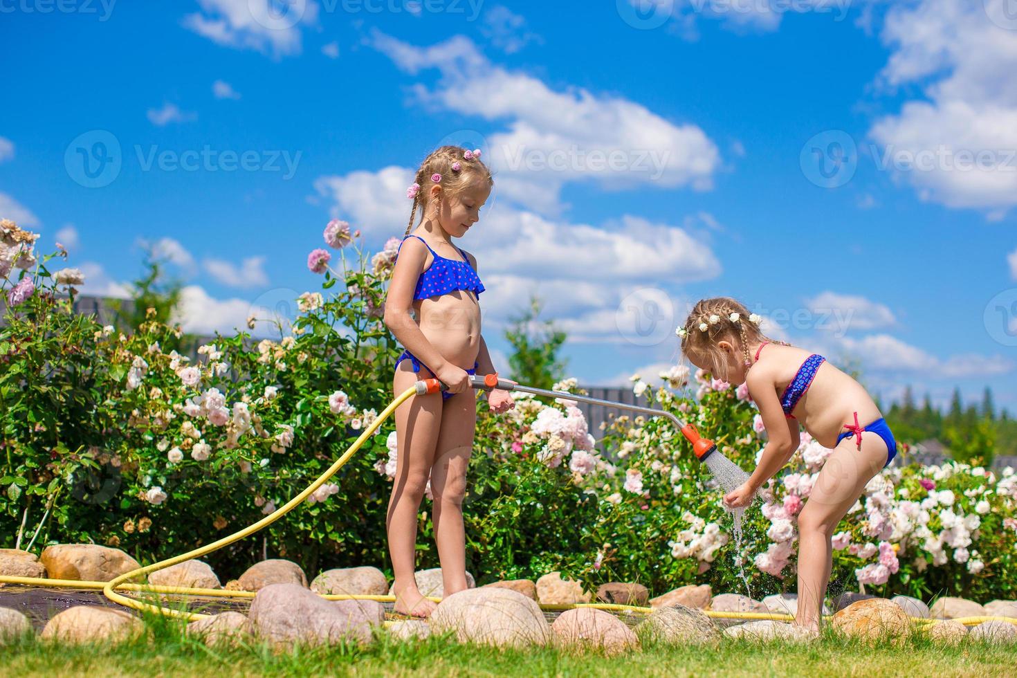 Little sisters having fun with a rose on the garden photo
