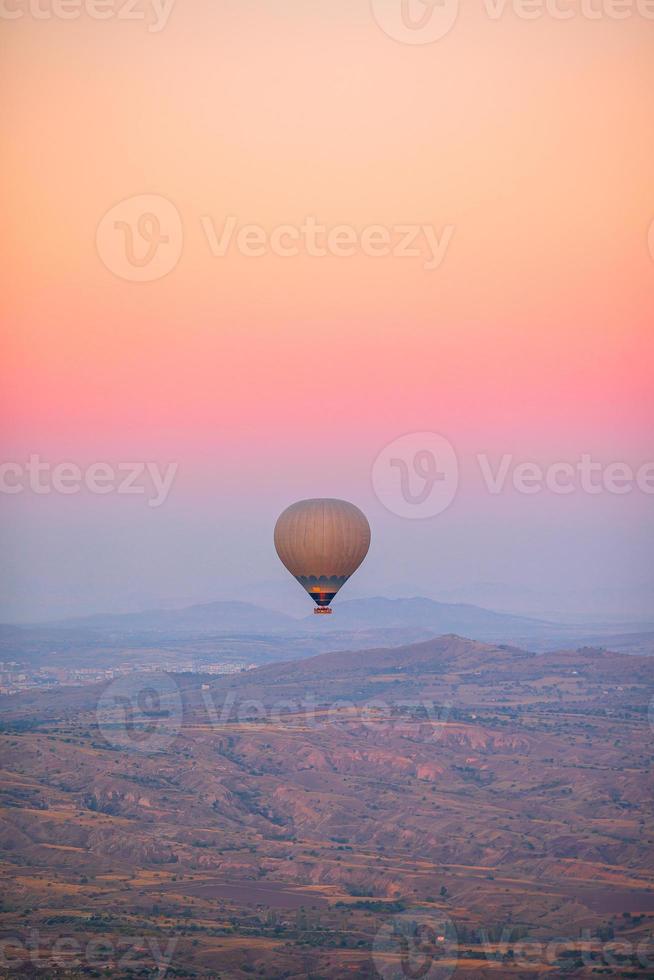 Hot air balloon flying over rocky landscapes in Cappadocia with beautiful sky on background photo