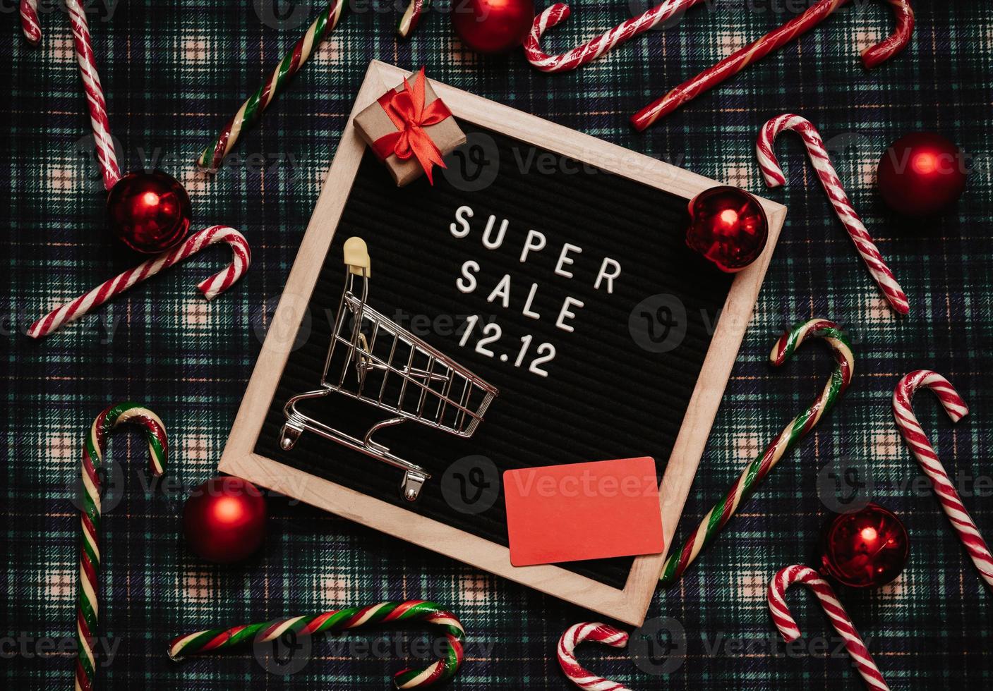 The text of the sale 12.12 on the Christmas decor letter board with a credit card and a mini grocery cart. Design to promote the winter sale at the end of the year. Top view. photo