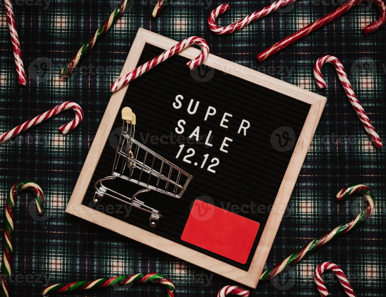 The text of the sale 12.12 on the Christmas decor letter board with a credit card and a mini grocery cart. Design to promote the winter sale at the end of the year. Top view. photo