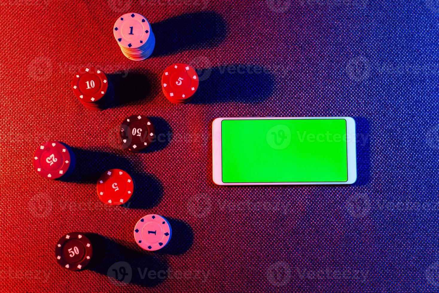 The concept of an online casino betting chips and a smartphone with a green background with a copy space. Top view. photo
