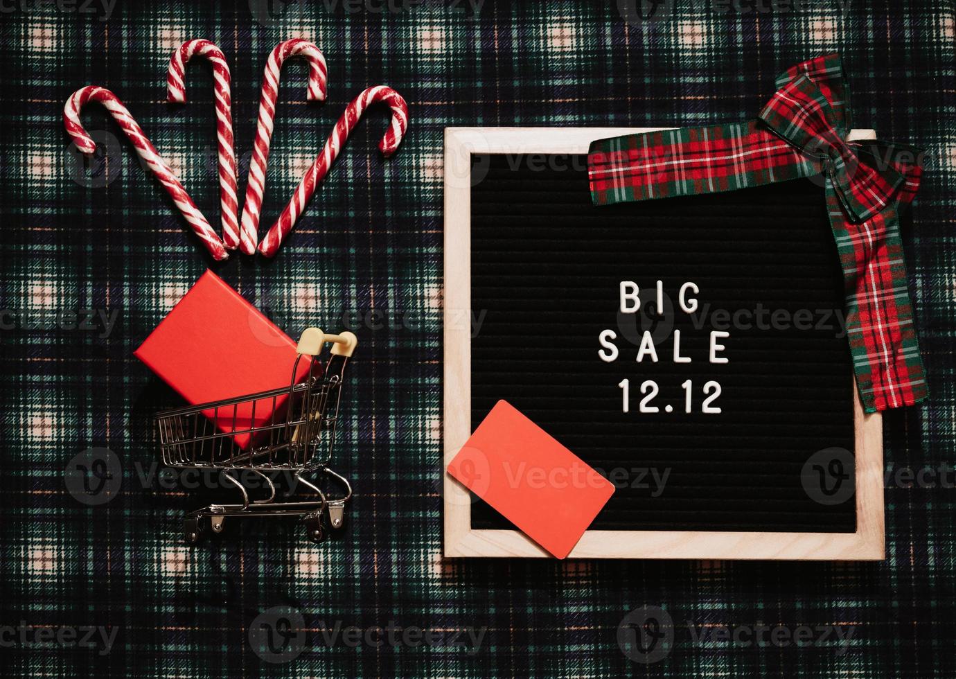 The text of the sale 12.12 on a message board with a gift box, credit card, mini grocery cart. Design to promote the winter sale at the end of the year. Top view. photo