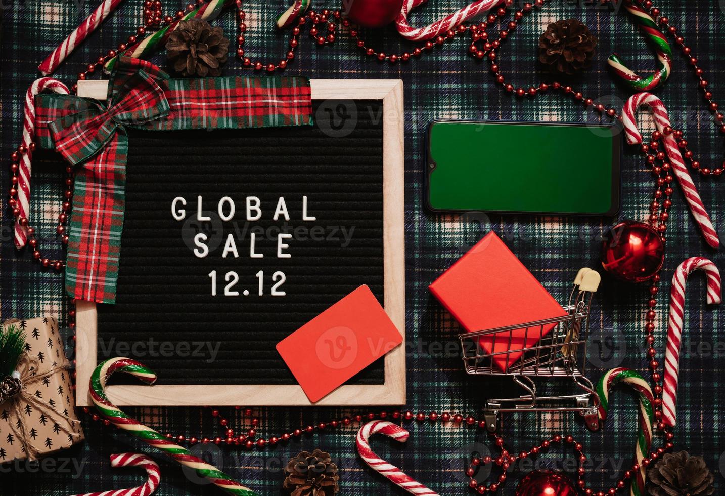 The text of the sale 12.12 on a letter board with Christmas decor, a credit card, a mini grocery cart and a phone with a chrome screen. Design to promote the winter sale at the end of the year. photo