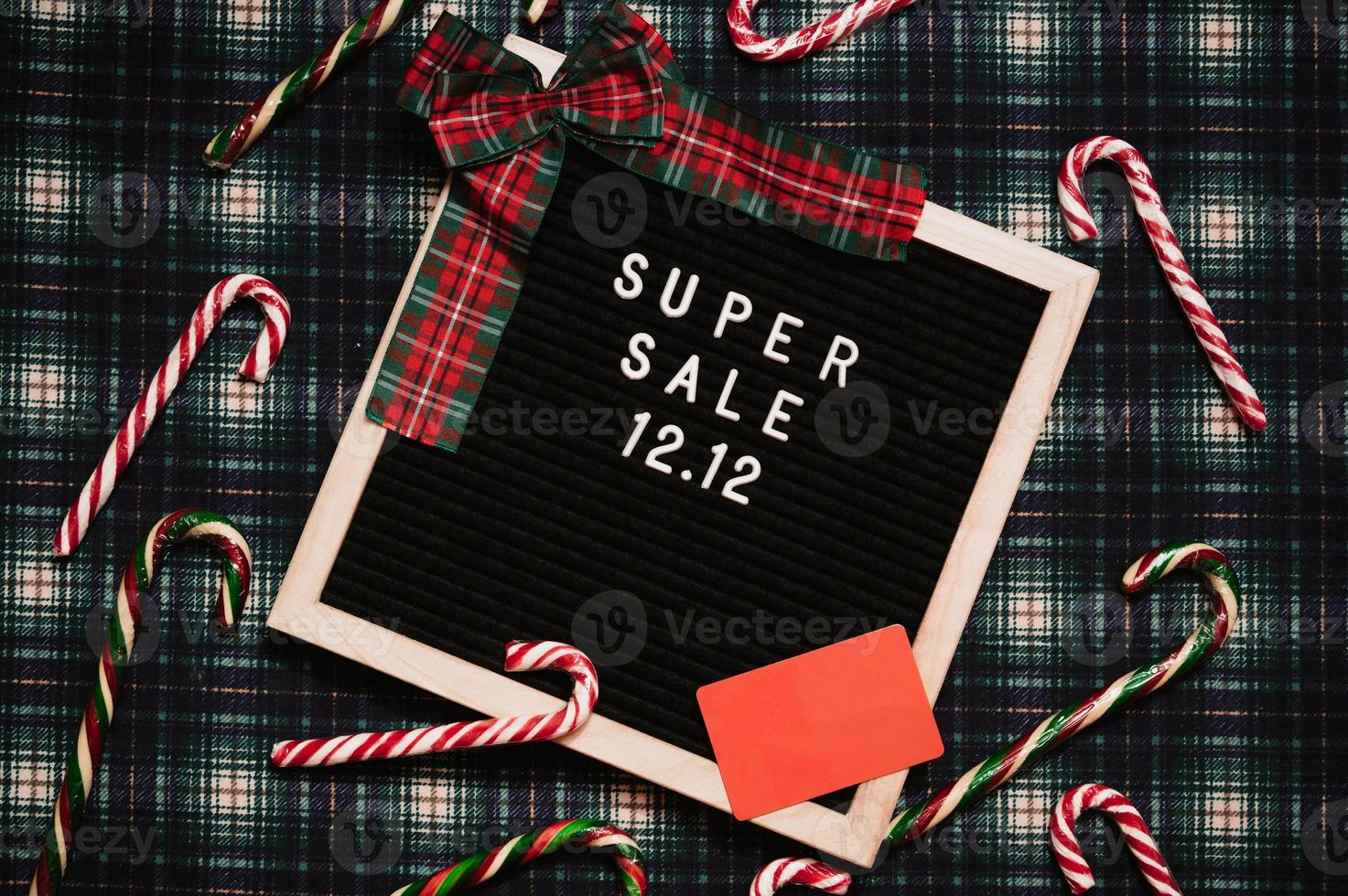 The text of the sale 12.12 on a letter board with a red gift box and Christmas candies, a credit card and a mini grocery cart. Design to promote the winter sale at the end of the year. Top view. photo