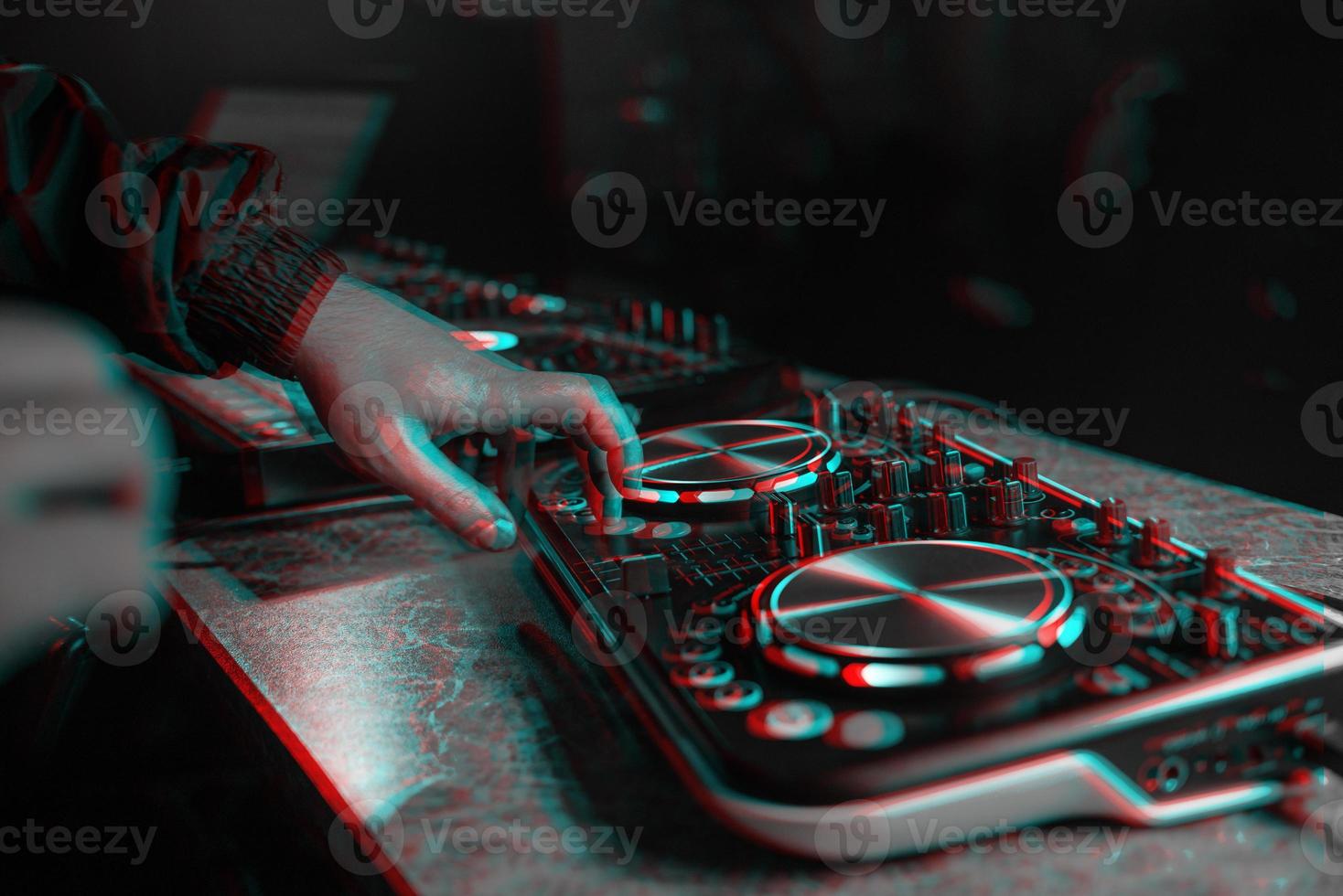 DJ console for mixing music with hands and with blurred people at a night club. Black and white with 3D glitch virtual reality effect photo