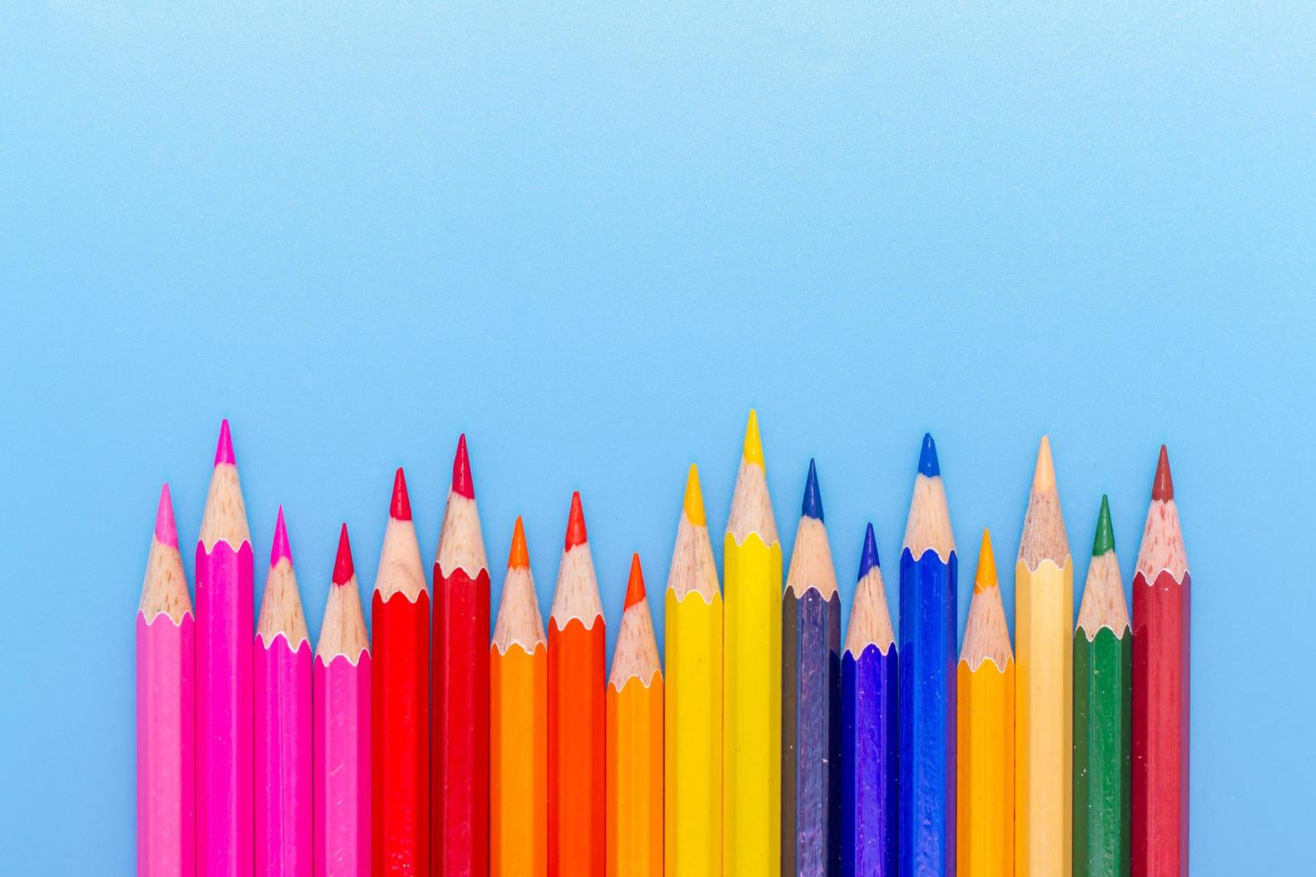 Collor wooden pencils in row isolated on bluebackground. Top view with copy space. photo