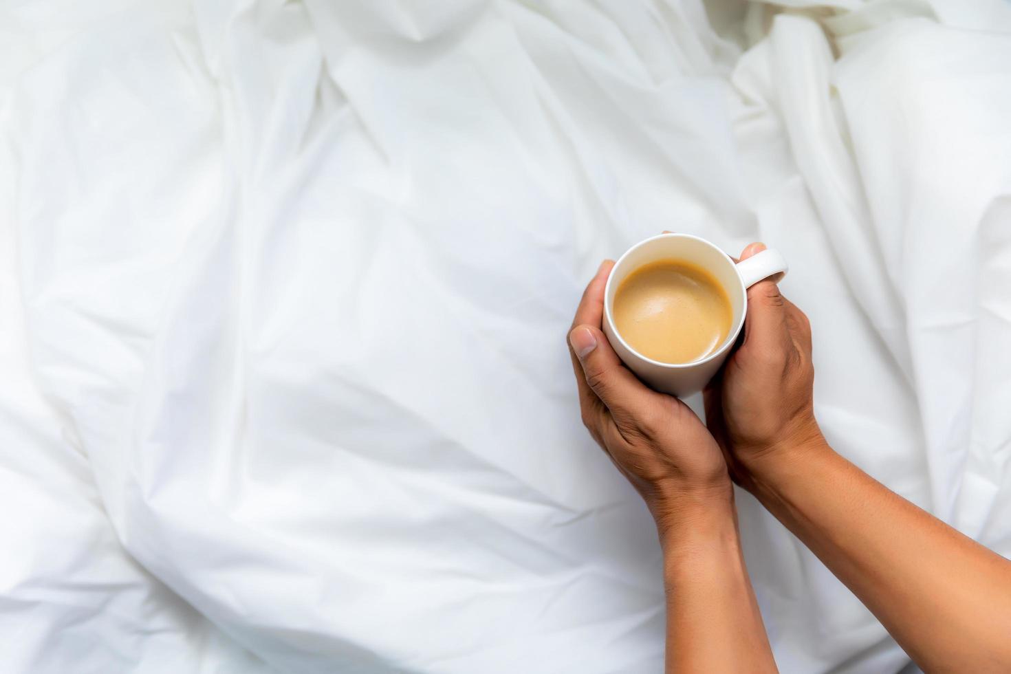 Man hand holding coffee cup on white cloth Top view photo