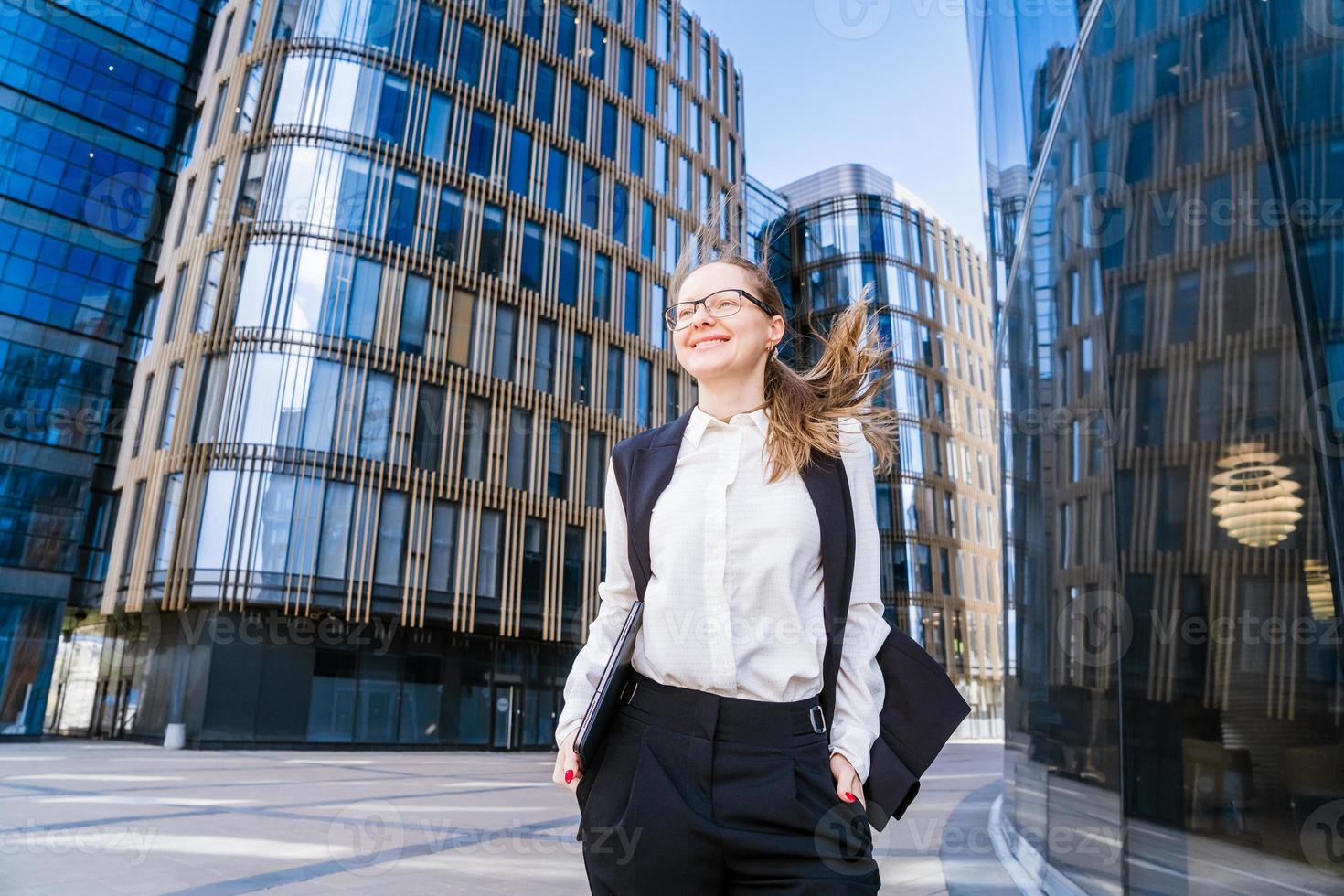 Portrait happy business woman who looks confident in a suit and glasses stands photo