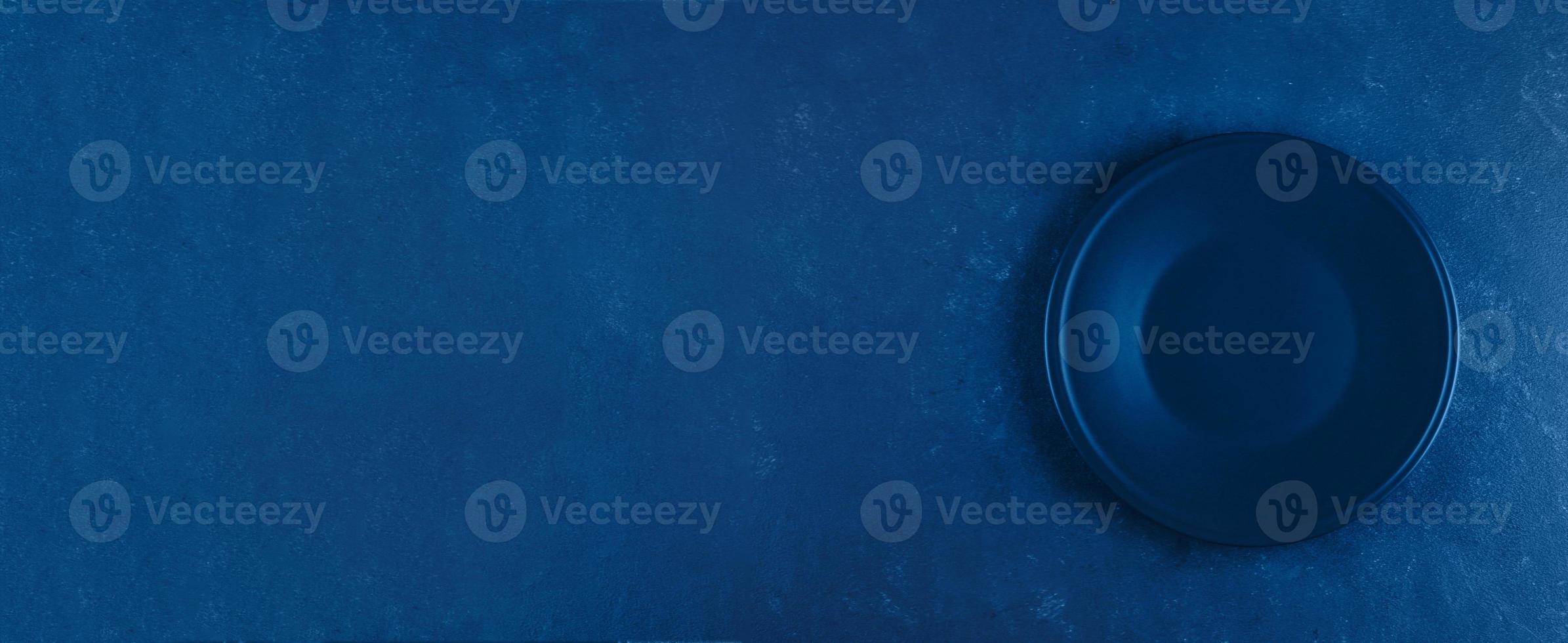 Empty plate on blue concrete background. Classic blue. Trend color of 2020 year. Banner for website photo