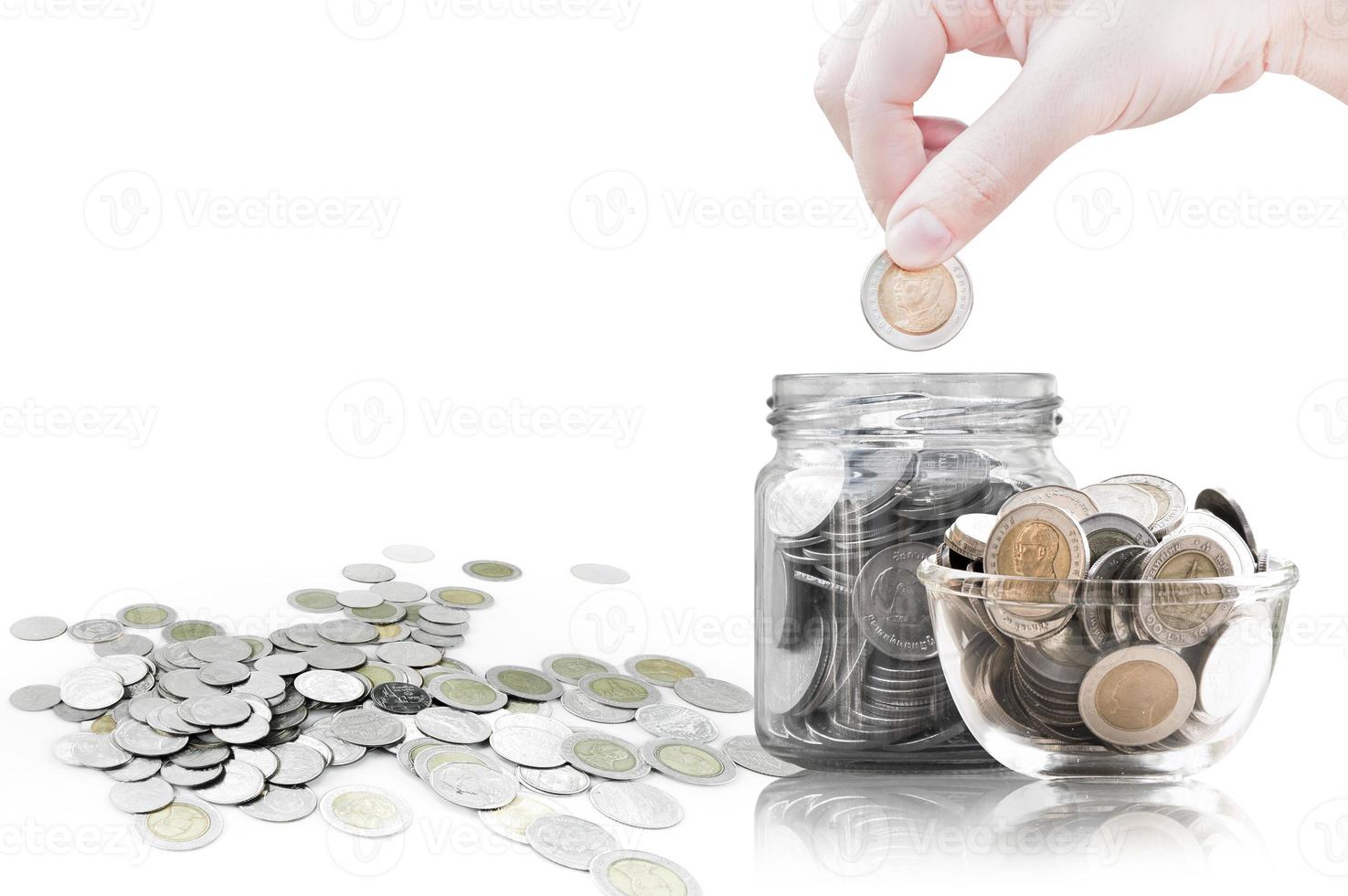 Hand putting coin into glass container,coins in a glass jar against ,savings coins - Investment And Interest Concept saving money concept, growing money on piggy bank. isolated on white background photo