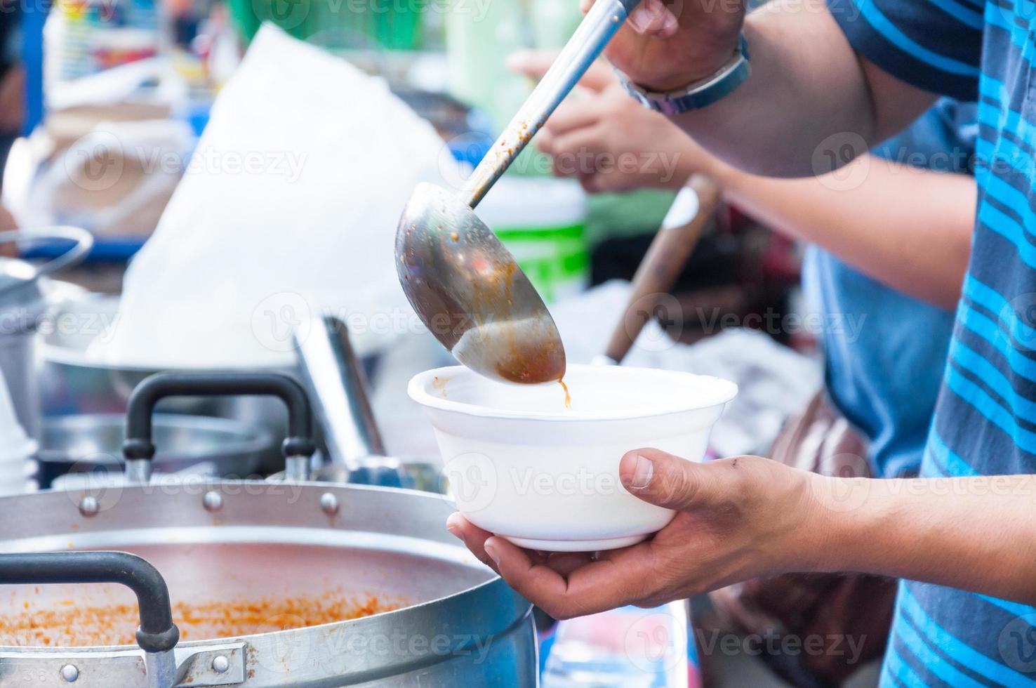 hand  holding Spoon food in the foam tray ,streetfood photo