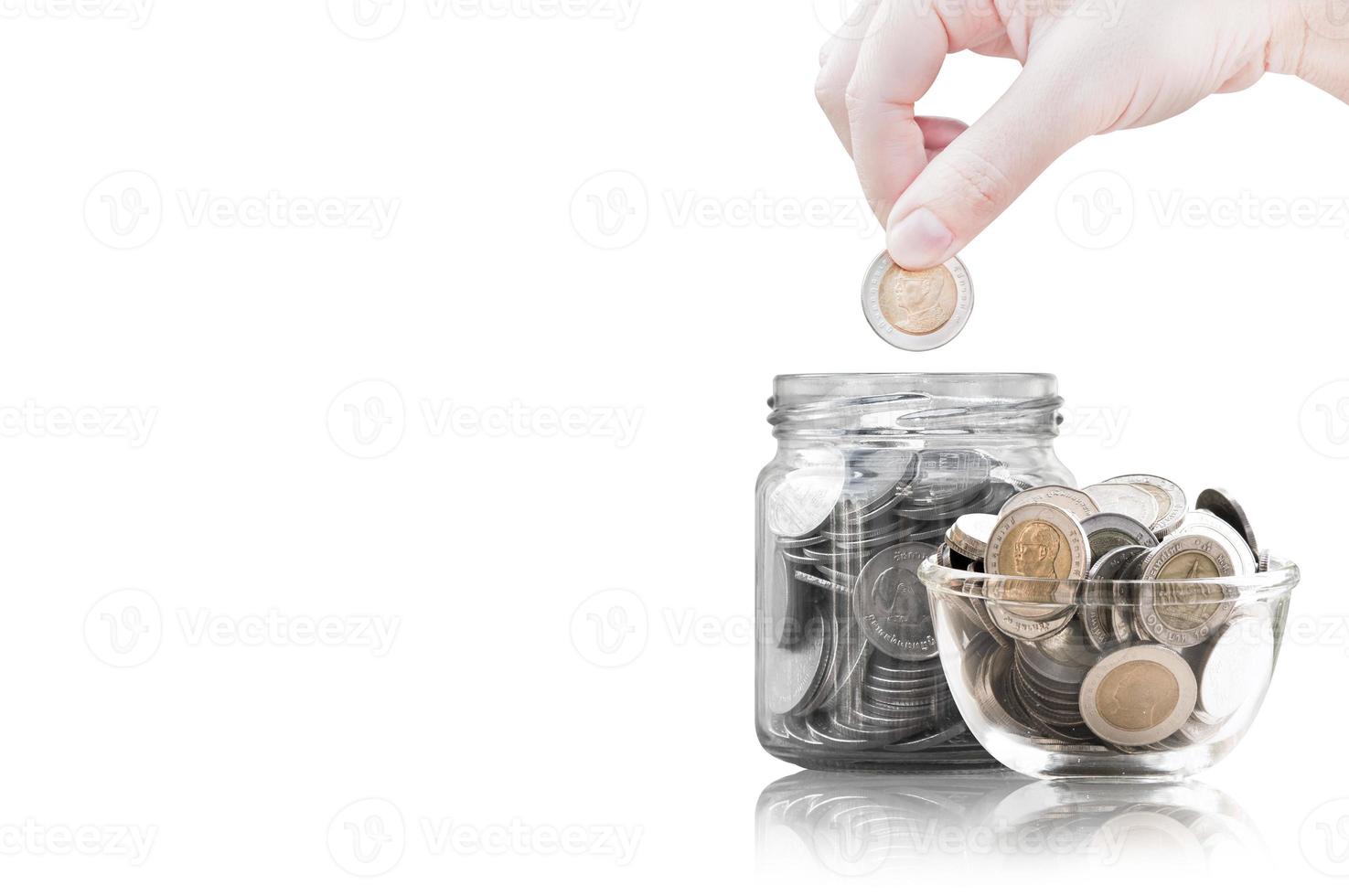 Hand putting coin into glass container,coins in a glass jar against ,savings coins - Investment And Interest Concept saving money concept, growing money on piggy bank. isolated on white background photo