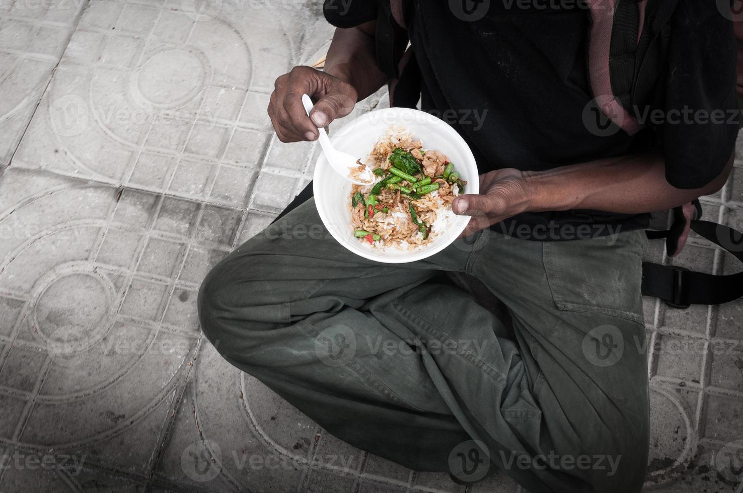 poor man homeless with dirty hands eating eating food at street road floor in the city modern capitalism society photo