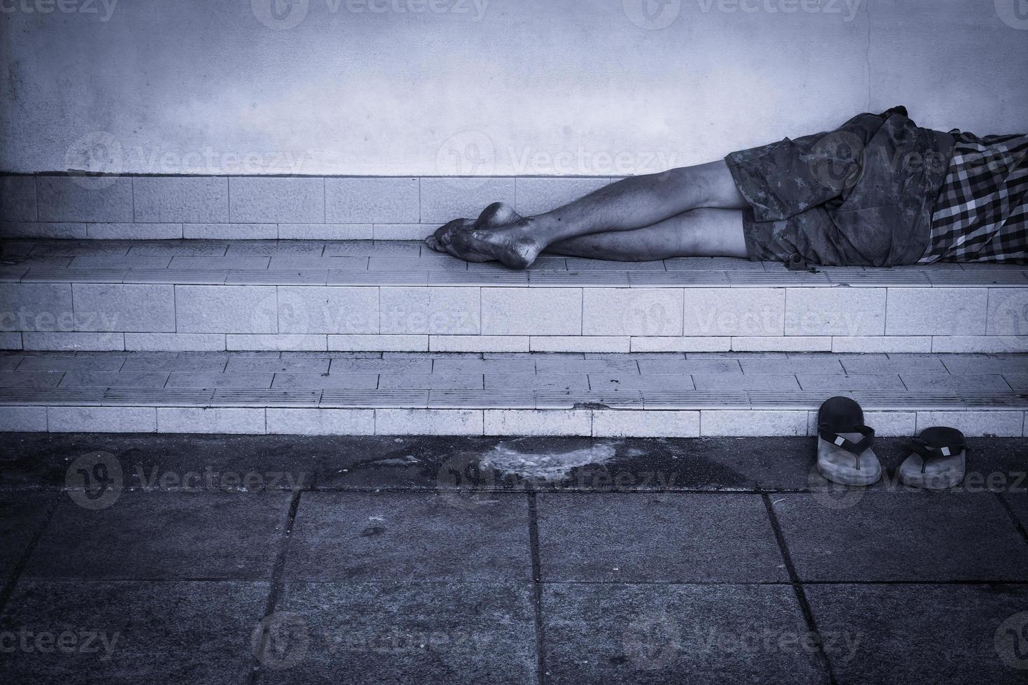 Vagabundo hombre sucio duerme en el calle en el sombra de el edificio. foto