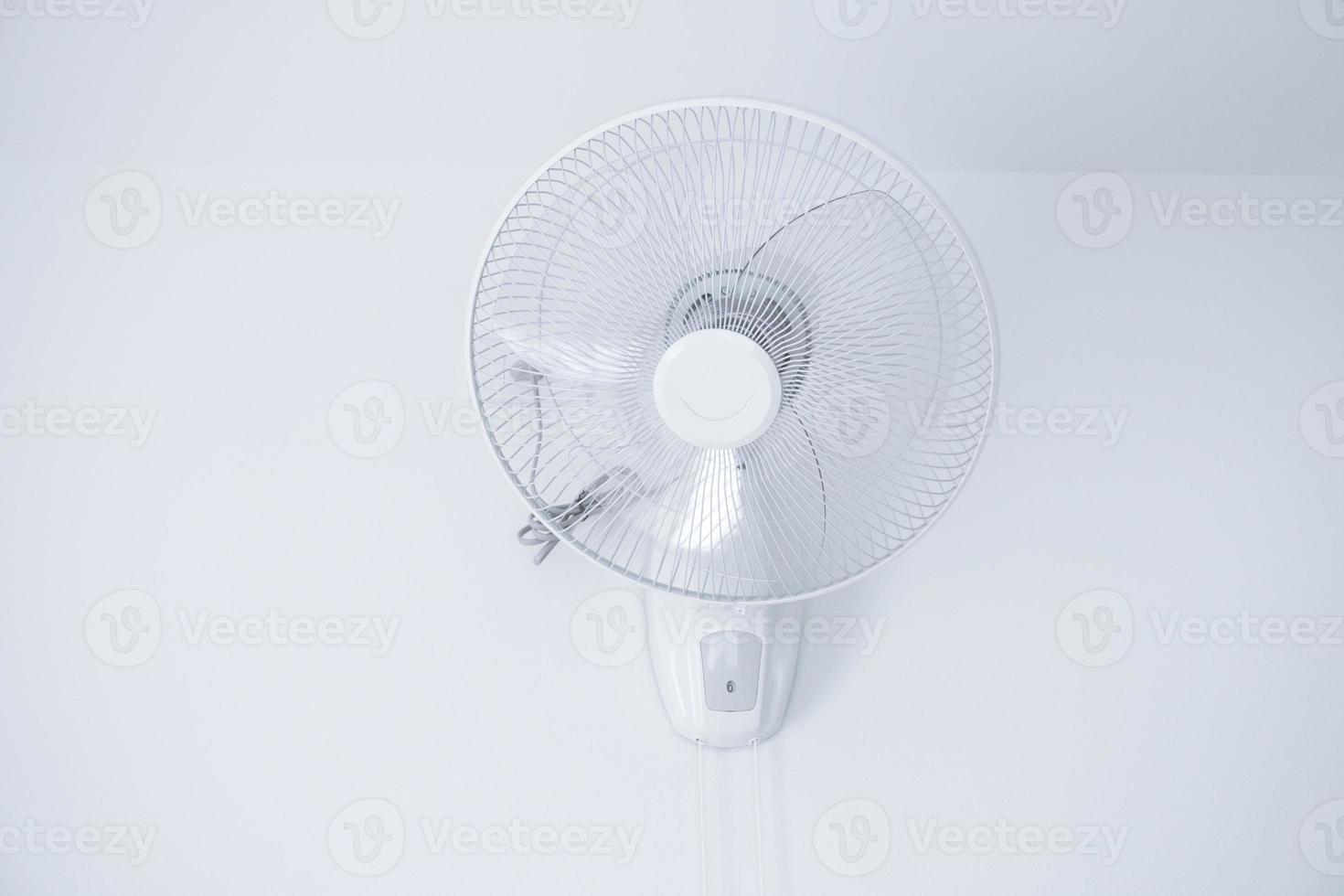 Wall mount electric white fan,electric fan hanging on white mortar wall photo