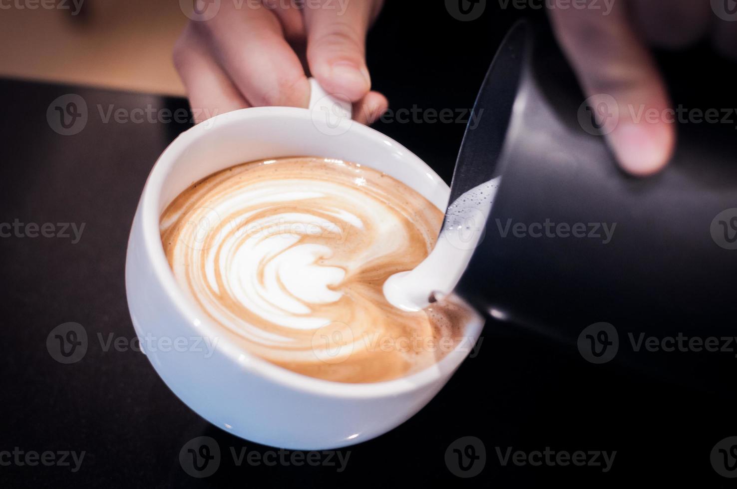 manos vertiendo leche y preparando capuchino fresco, artista del café y concepto de preparación, café recién hecho por la mañana, hora del café foto