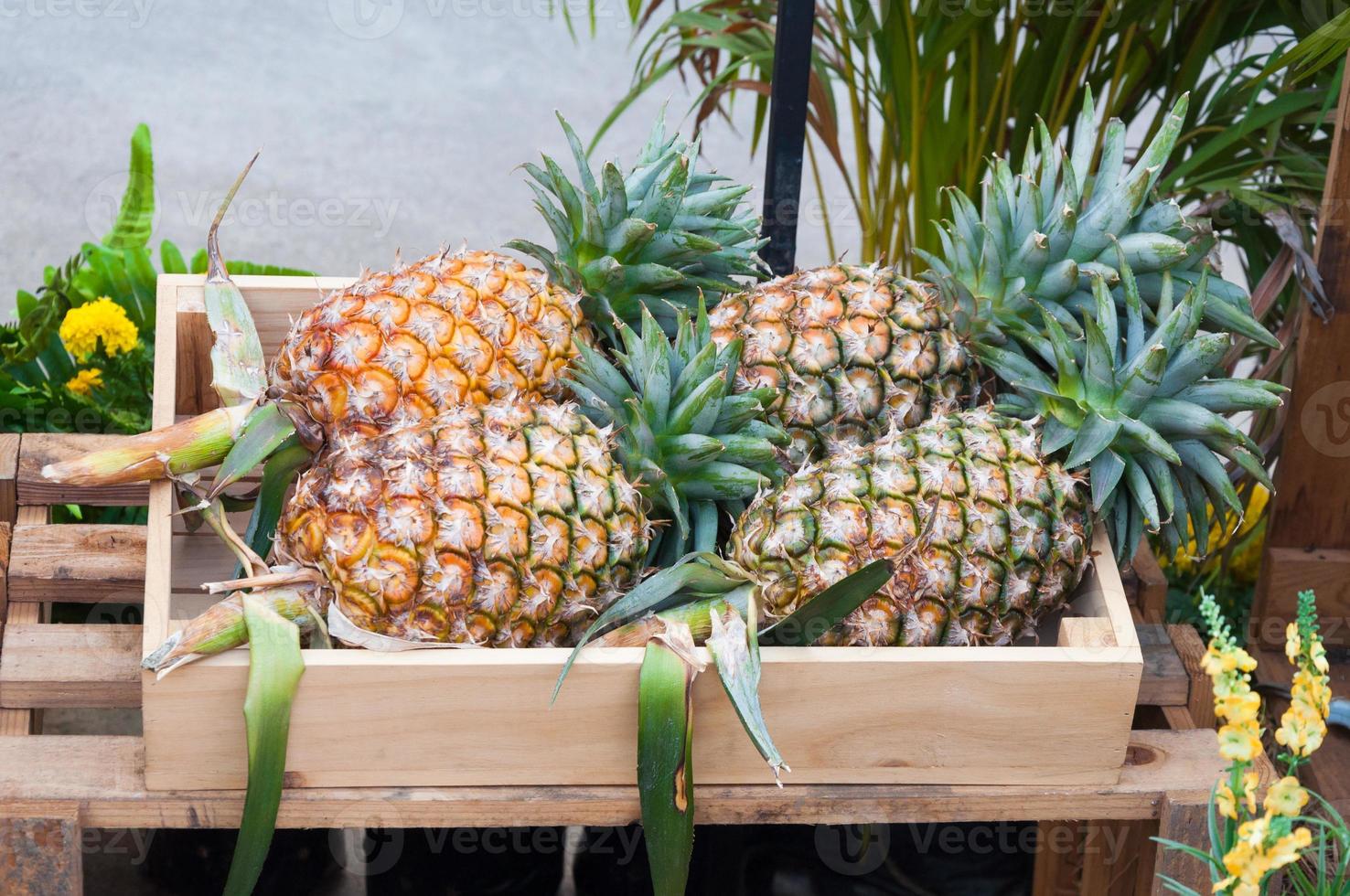 piñas frescas en caja de madera, mercado callejero foto