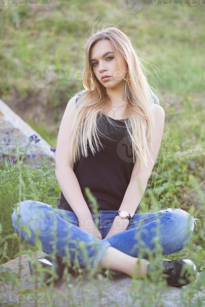 Young lovely woman posing sitting on a stone photo