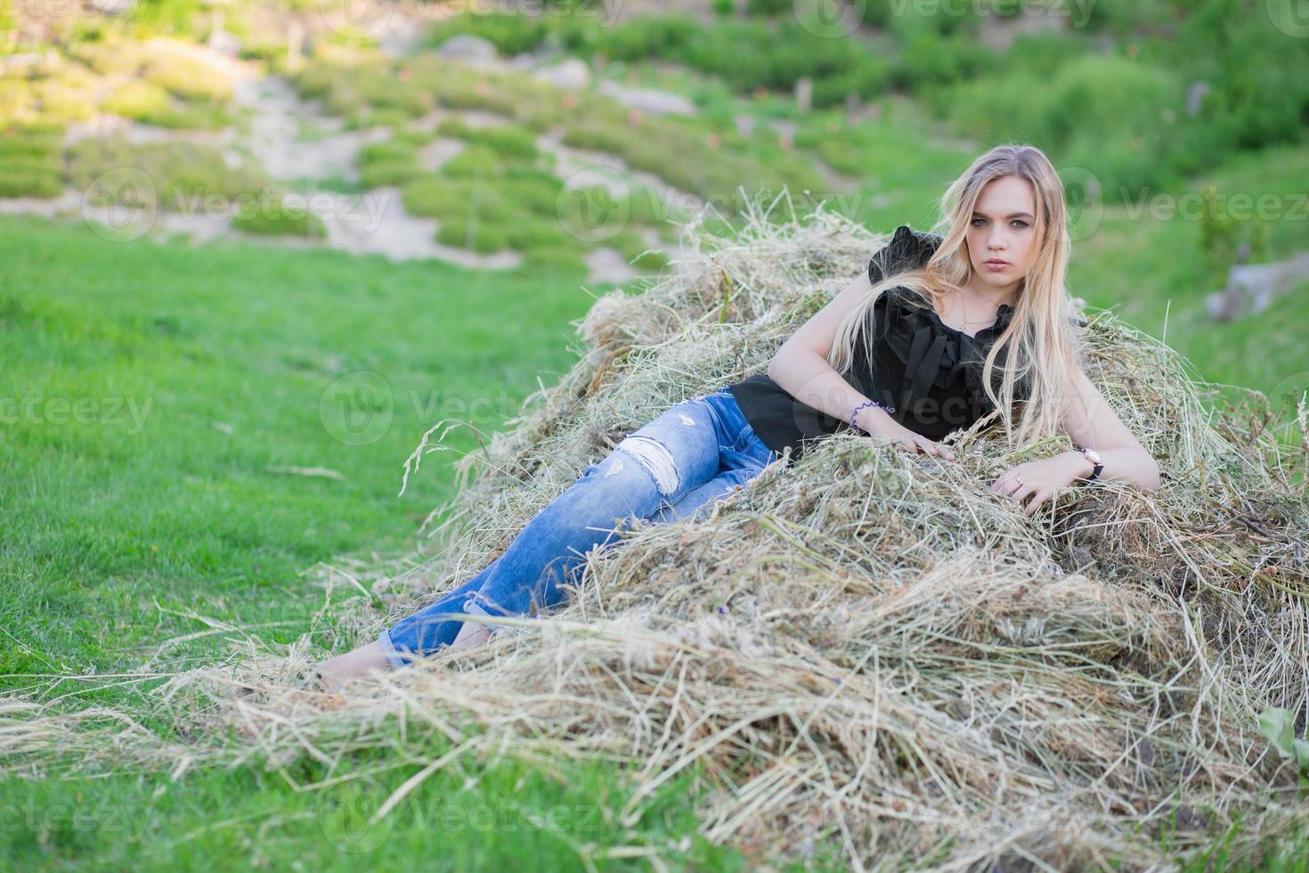 Beautiful woman posing sitting on the hay photo
