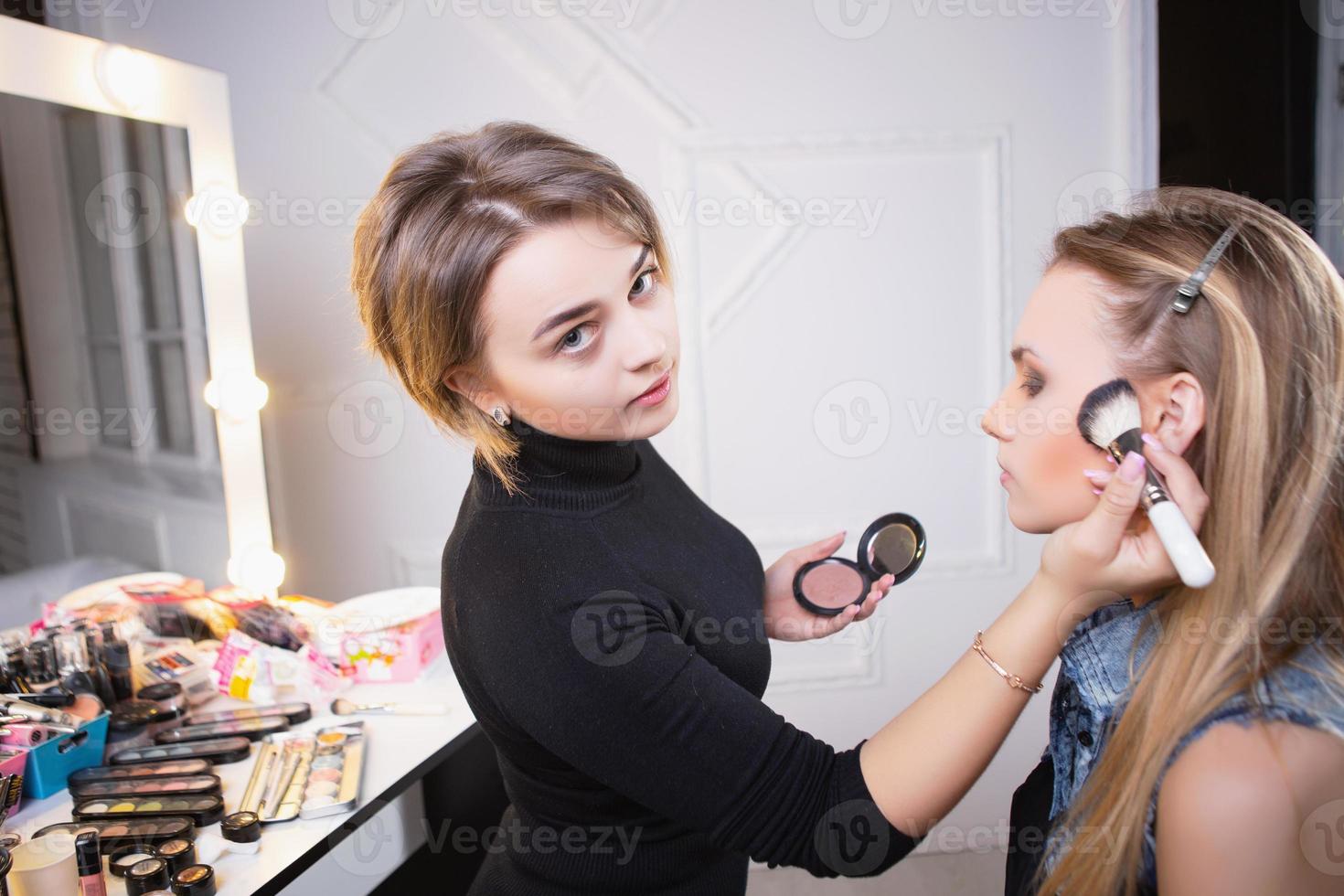 Makeup artist applying make up on attractive model photo