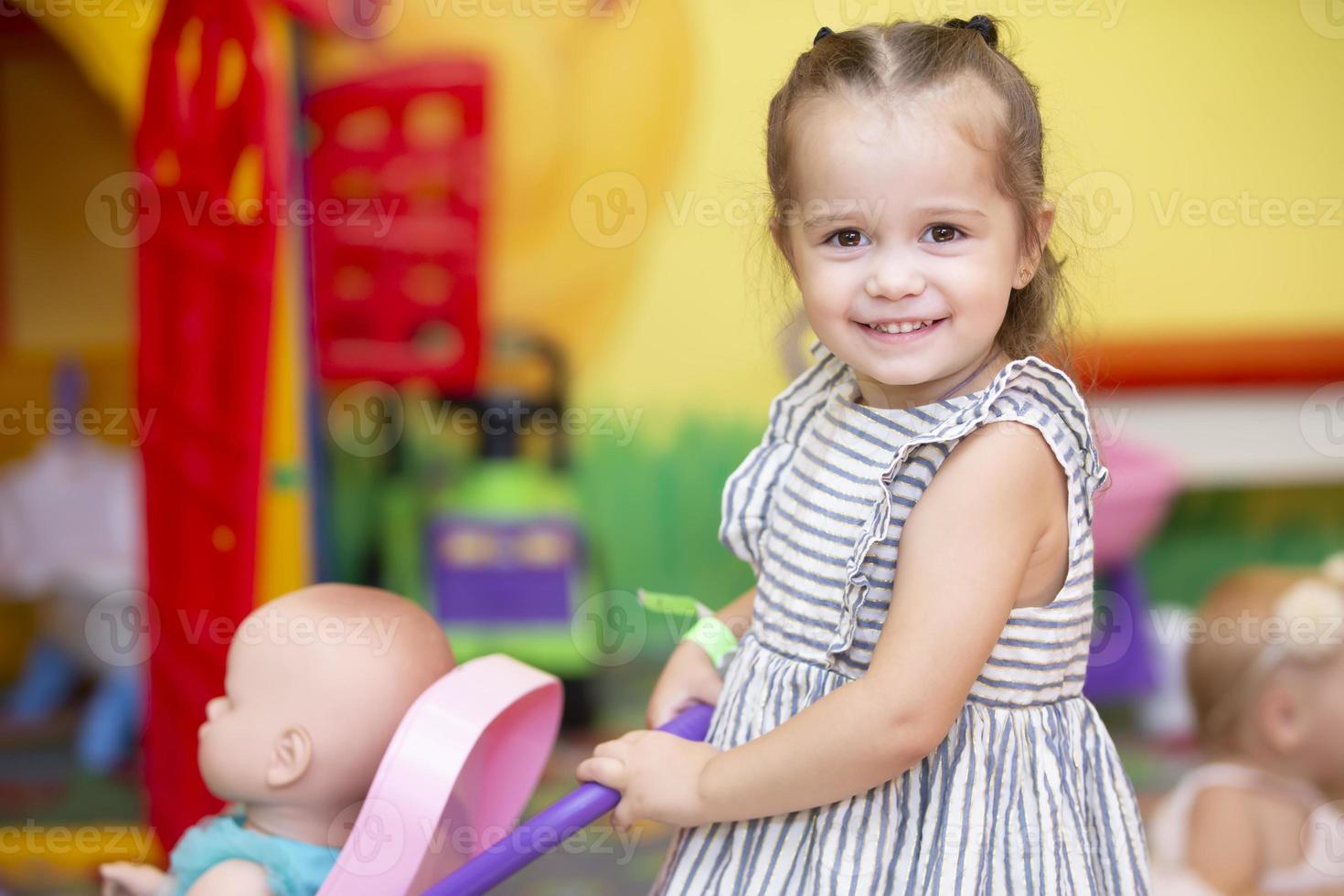 Little girl plays with a doll and smiles. photo