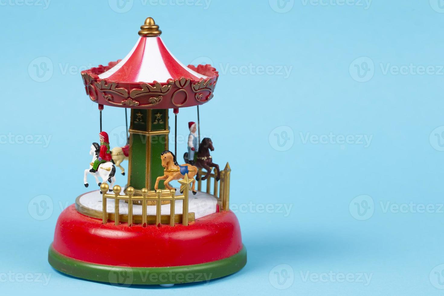 Vintage toy carousel on a blue background. Red carillon with carousel