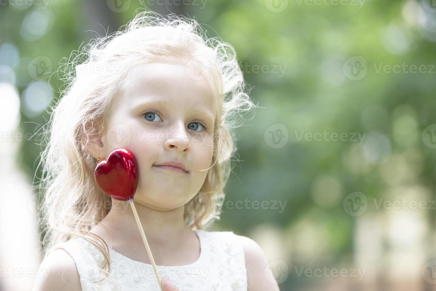 Little girl holding a small red heart. Child with a toy heart. photo