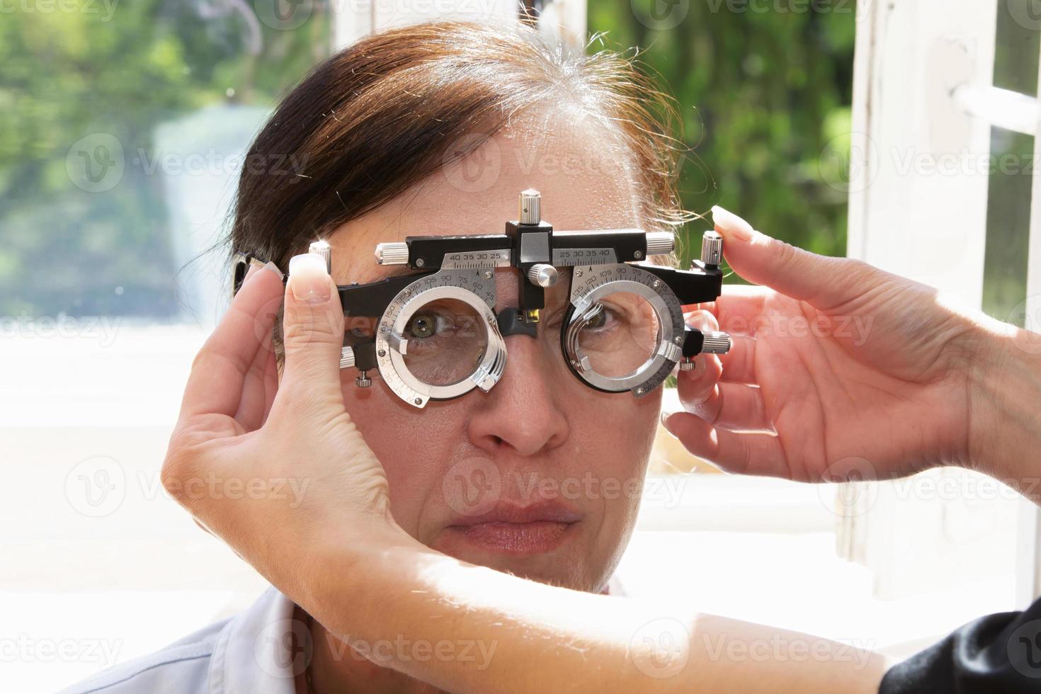 An ophthalmologist selects glasses for a woman with a set of trial spectacle lenses. A patient at an ophthalmologist's appointment. photo