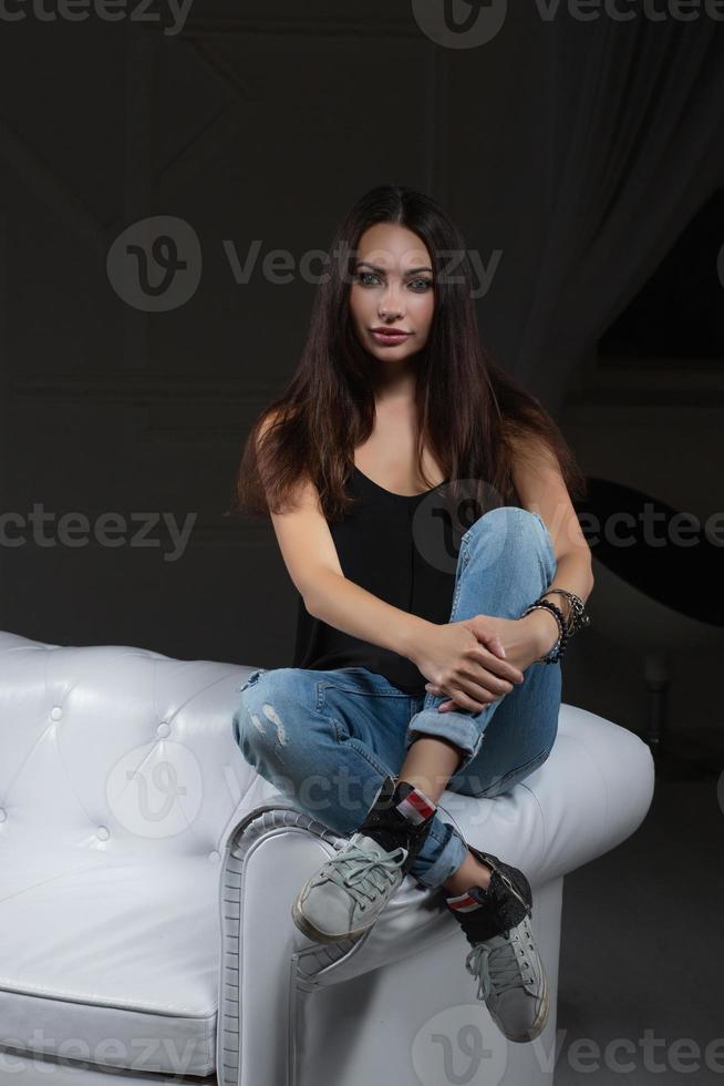 Beautiful brunette posing sitting on a sofa photo