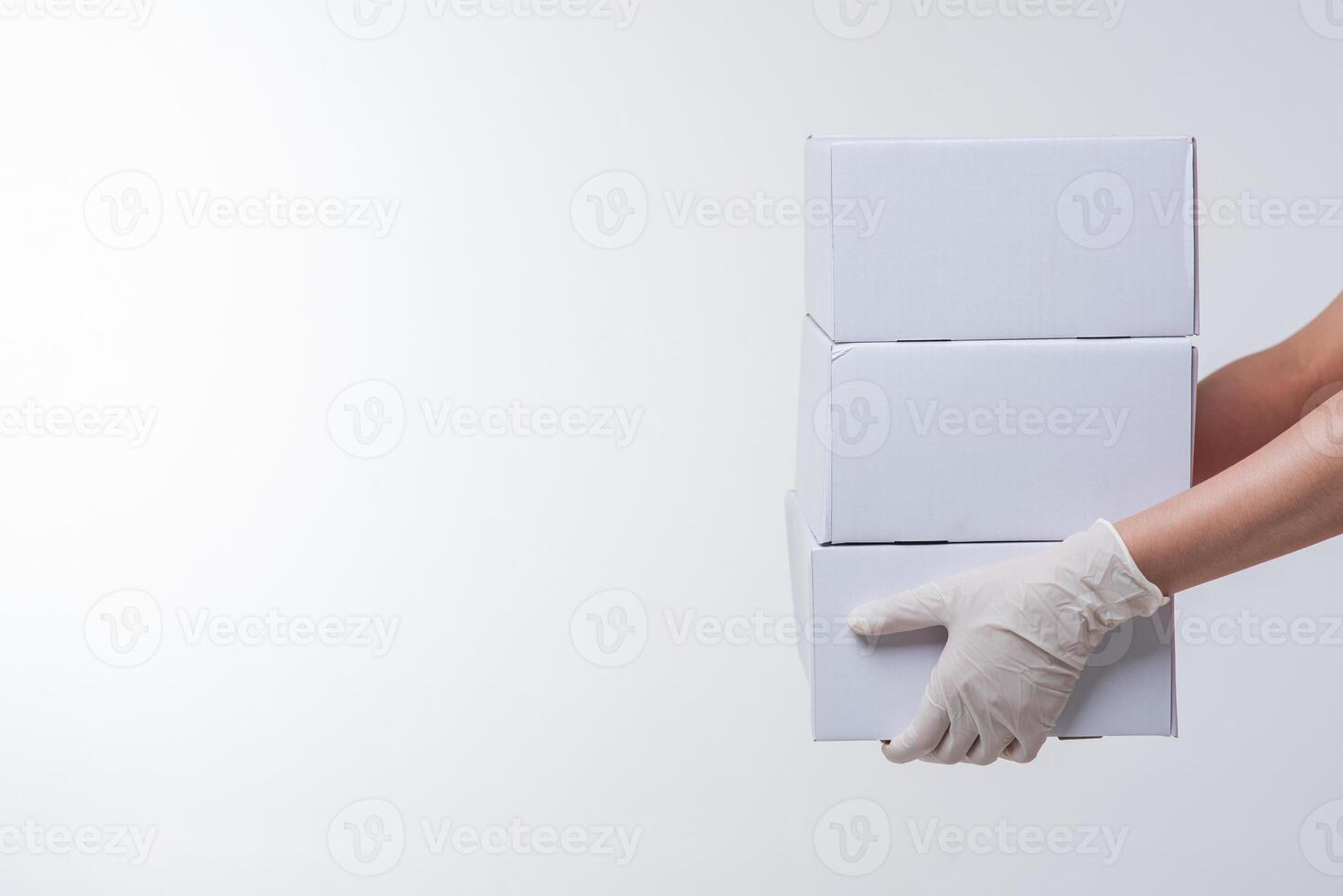 Image of  young delivery man in red cap blank t-shirt uniform standing with empty white cardboard box isolated on light gray background studio photo