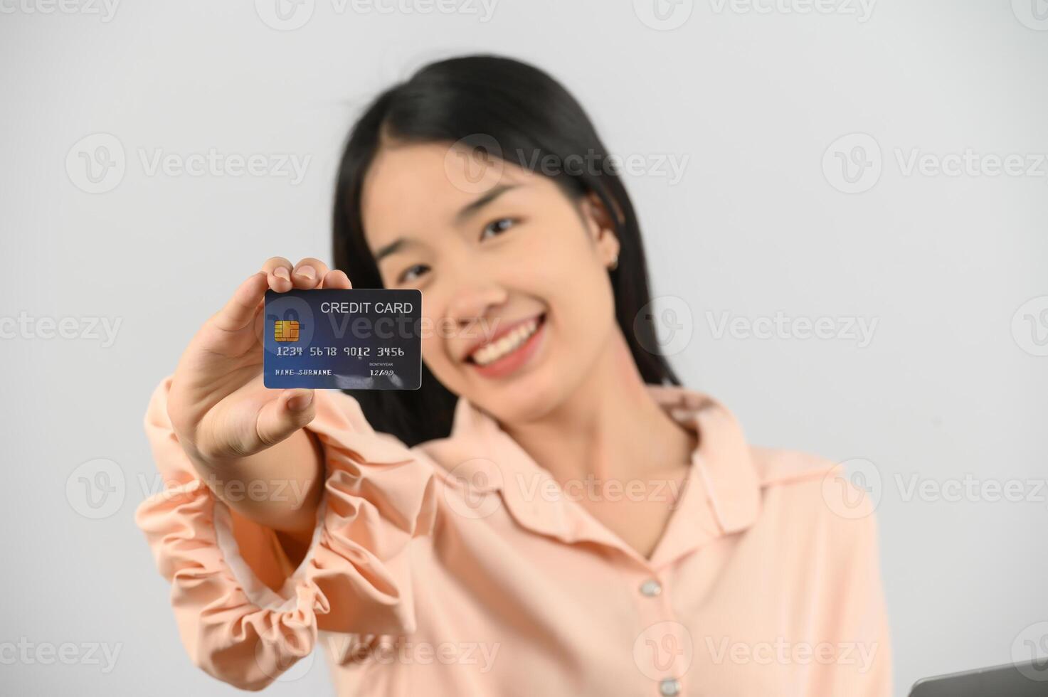 Portrait of positive young asian woman showing credit card good mood salary isolated on white background photo