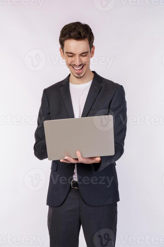 Portrait of young handsome smiling businessman holding laptop in hands, typing and browsing web pages isolated on white background photo
