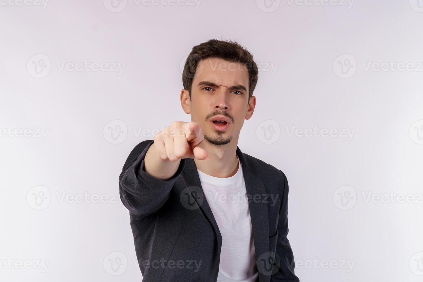 Portrait of attractive cheerful young man pointing finger at camera and standing isolated over background photo