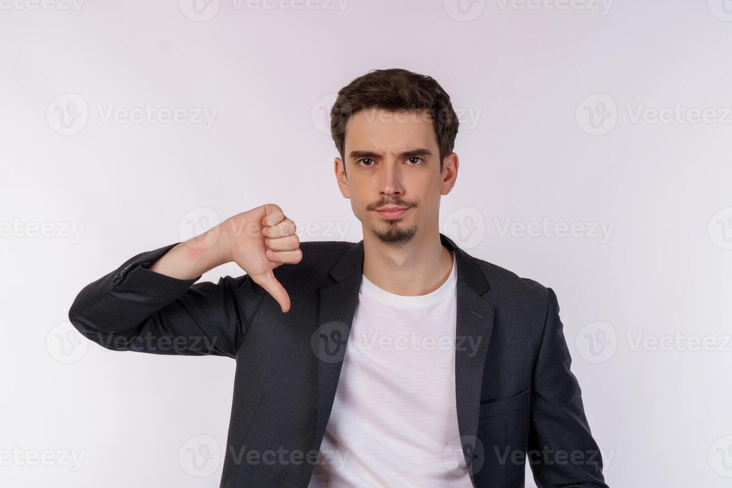 Portrait of young businessman shows sign of dislike, looks with negative expression and disapproval on isolated background photo