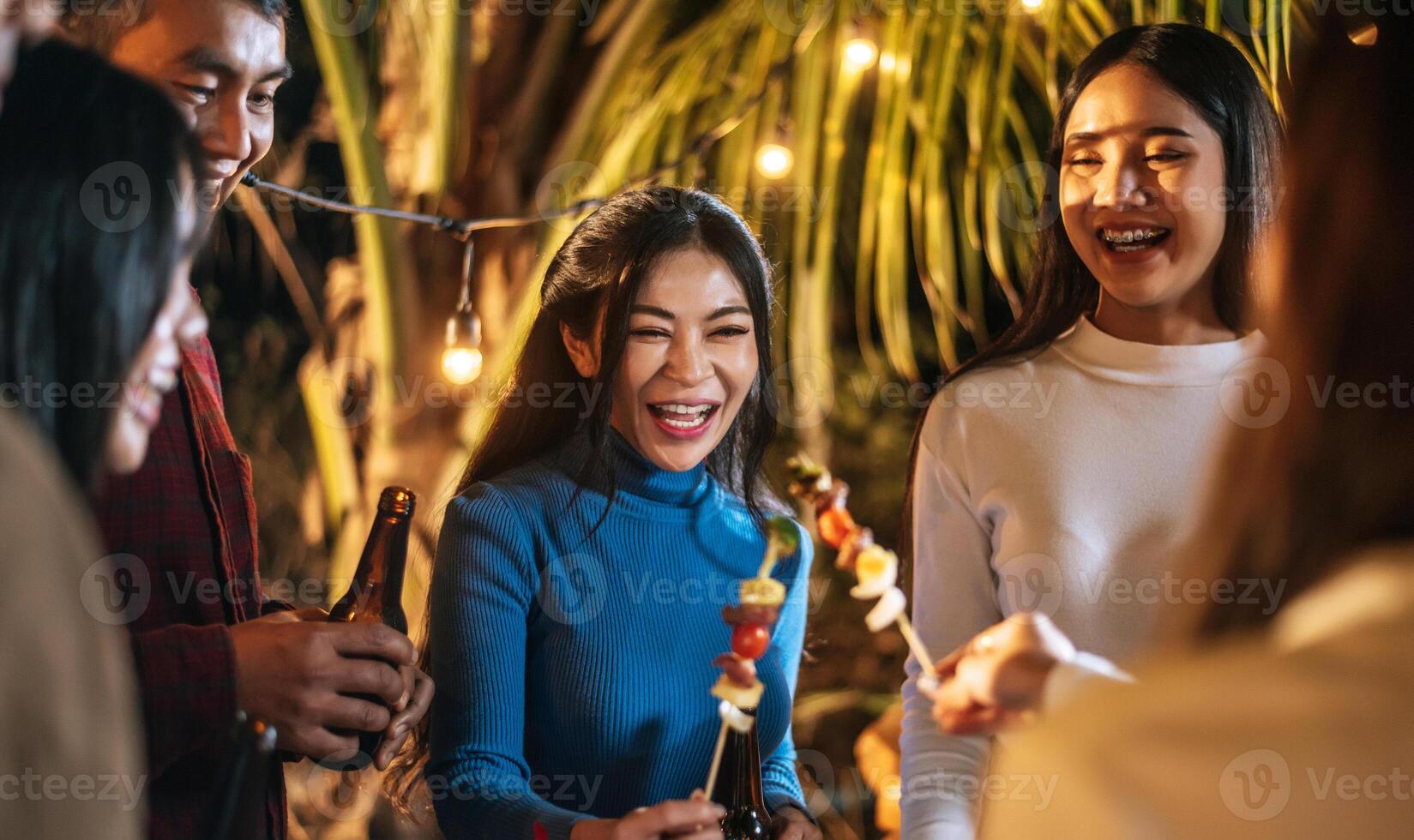 Happy Asian friends cheering with barbecue dinner outdoor - Group of people having fun in new year party. People, food and drink lifestyle concept Night Party, people and celebration concept. photo