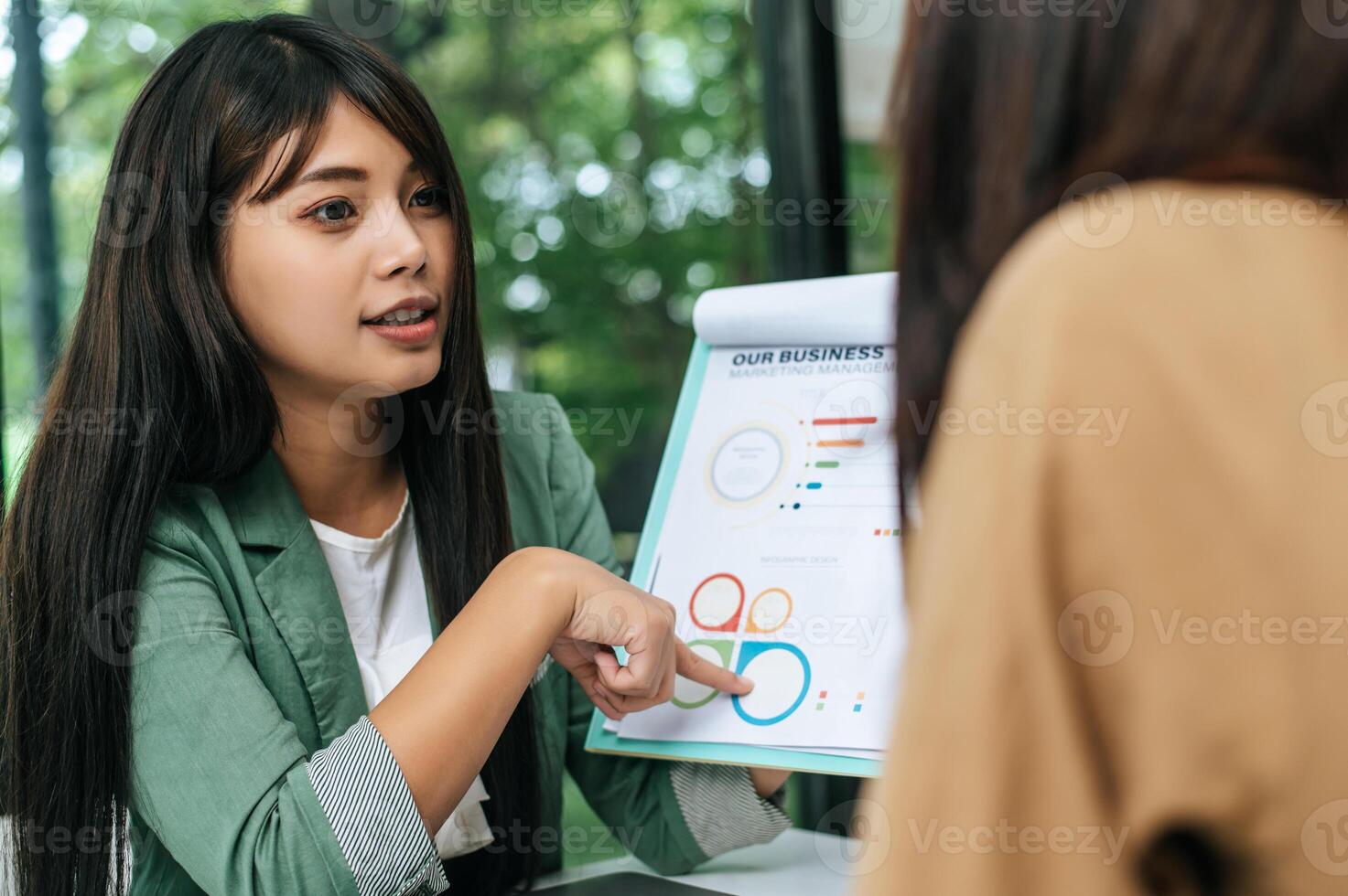 Young woman and friend working with paper work at coffee shop photo