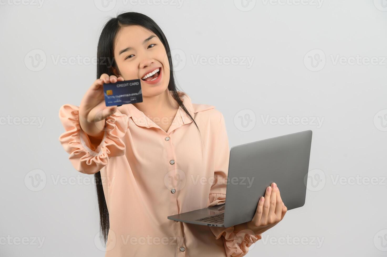 Portrait of a happy asian businesswoman working on laptop computer and showing credit card isolated over white background photo