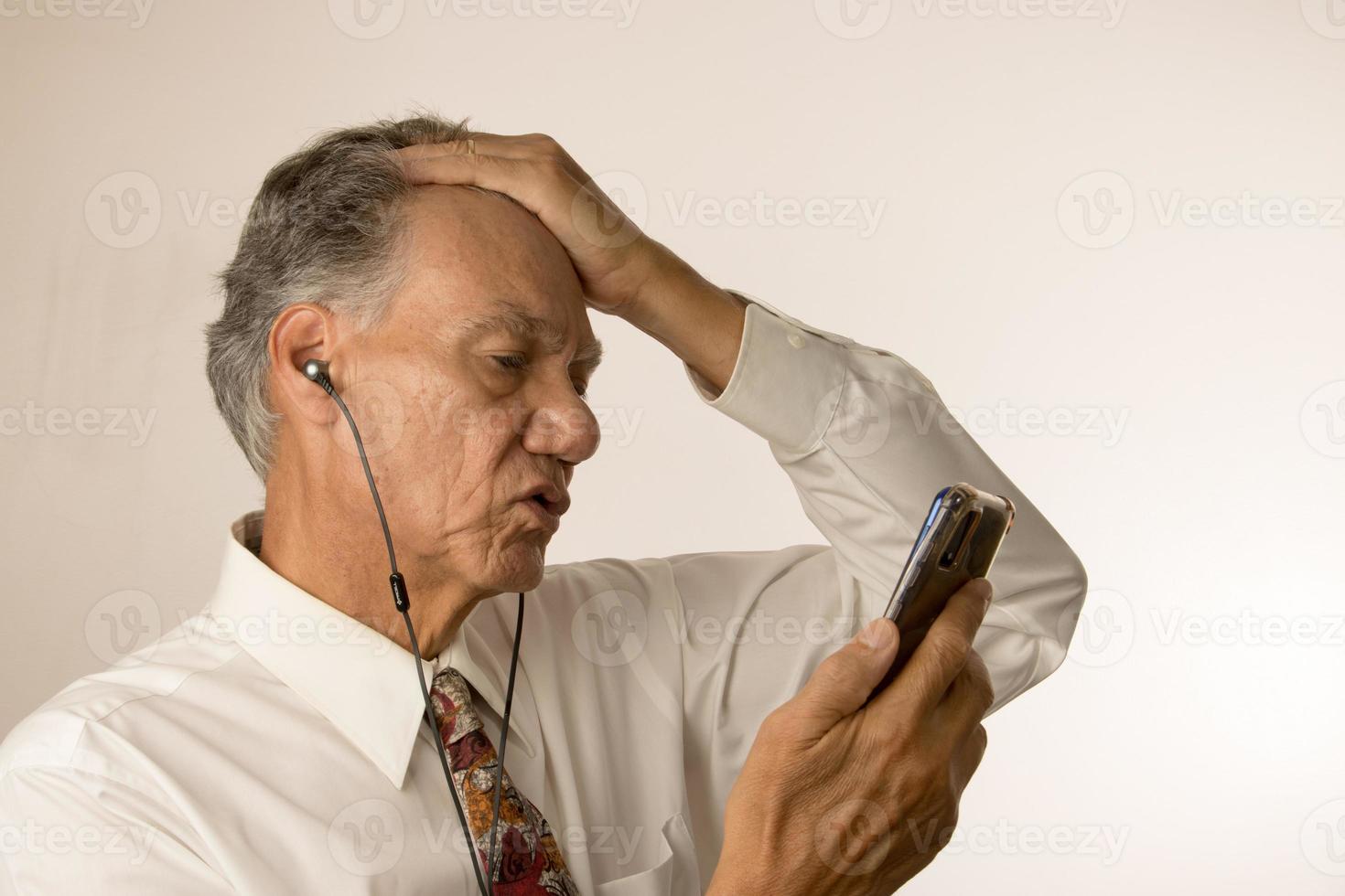 Older Man listening to music or a podcast using ear buds on his smartphone photo