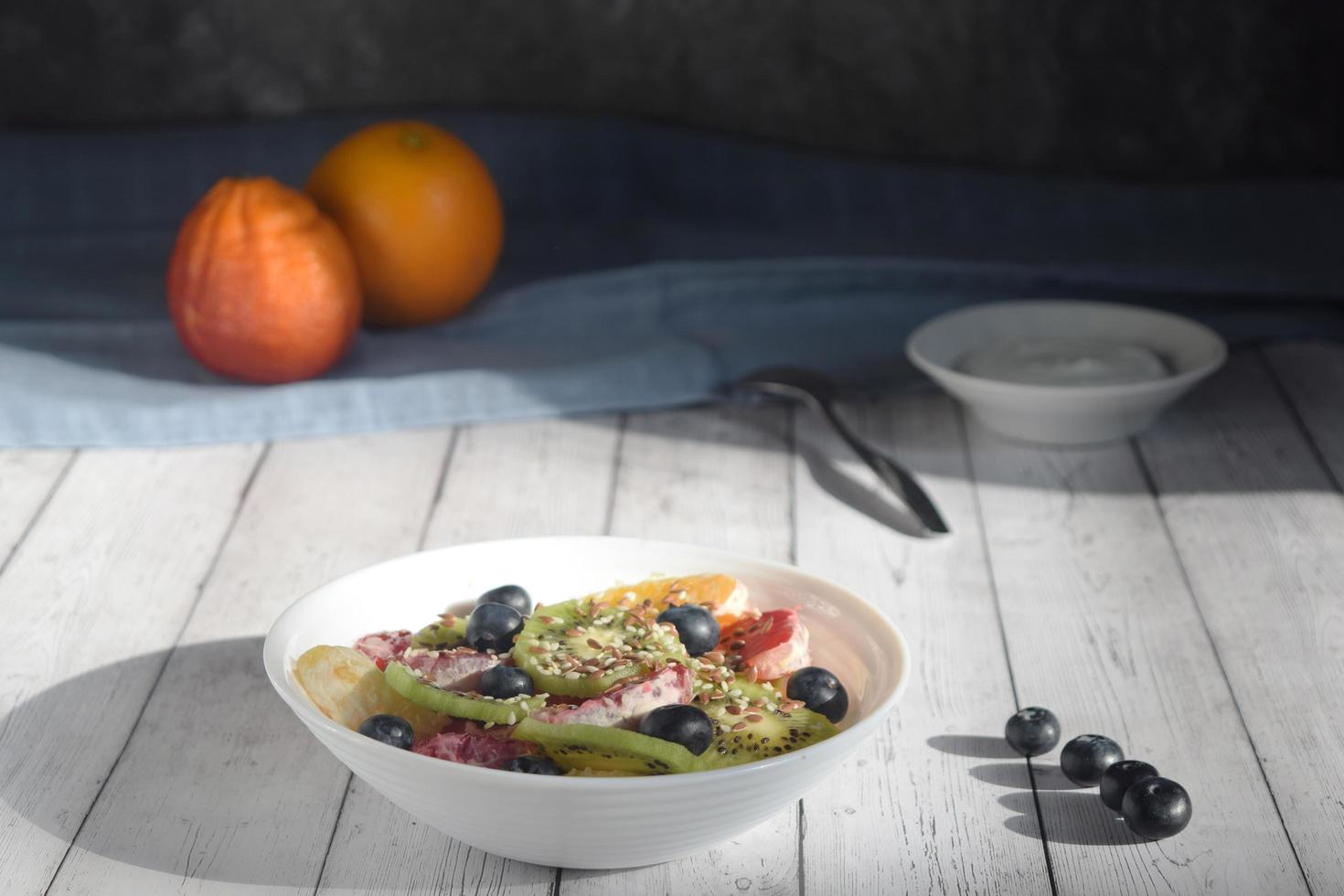 photo still life, plate with fruit salad, blueberry berries, spoon and yogurt , rustic