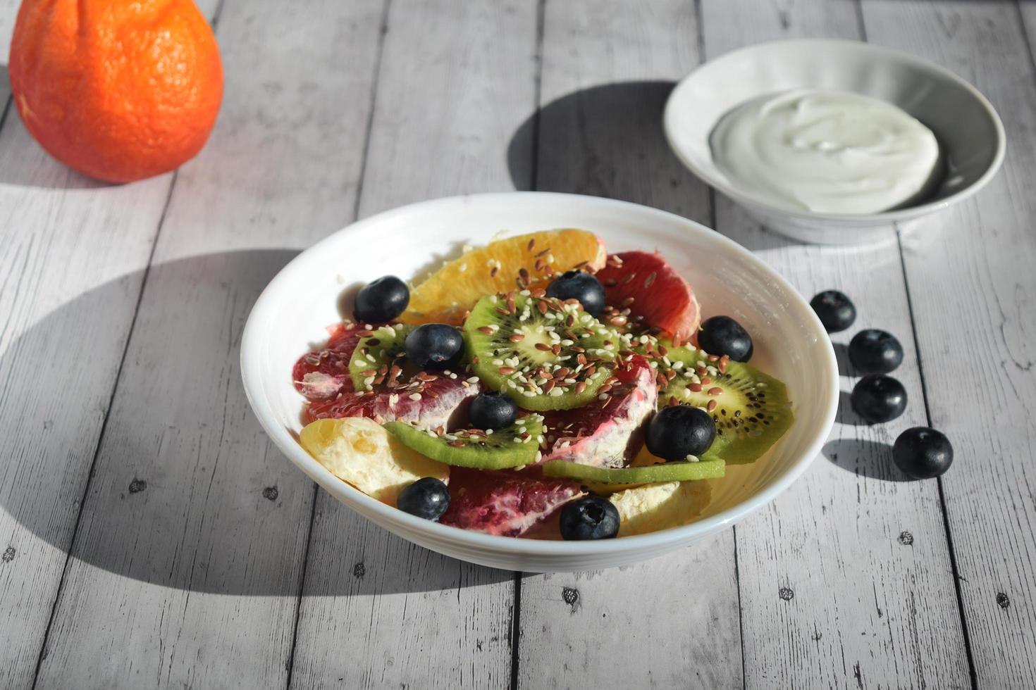 photo still life, plate with fruit salad, blueberry berries, spoon and yogurt , rustic