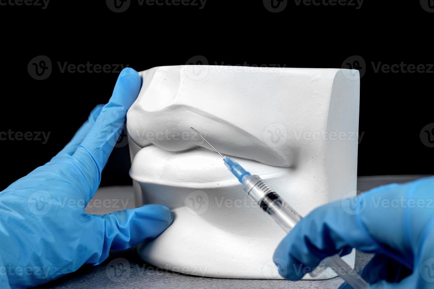 Close up hands of a cosmetologist making botox injections in plaster white female lips. Creative lip injection photo