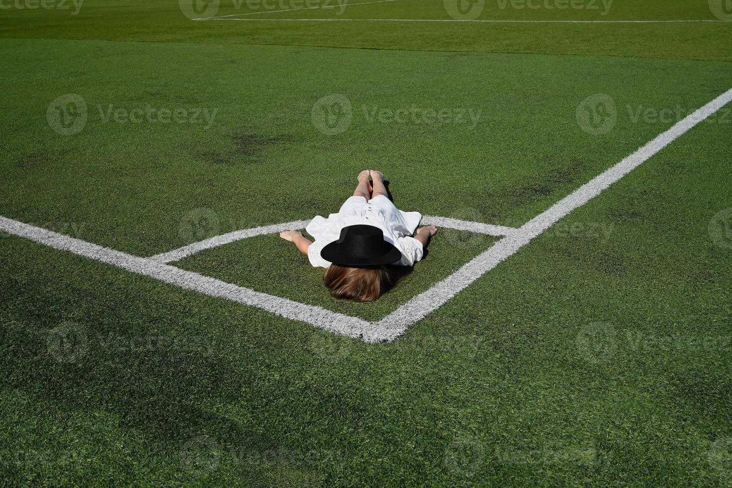 A girl in a hat, lying in the stadium. Active recreation in a white dress photo