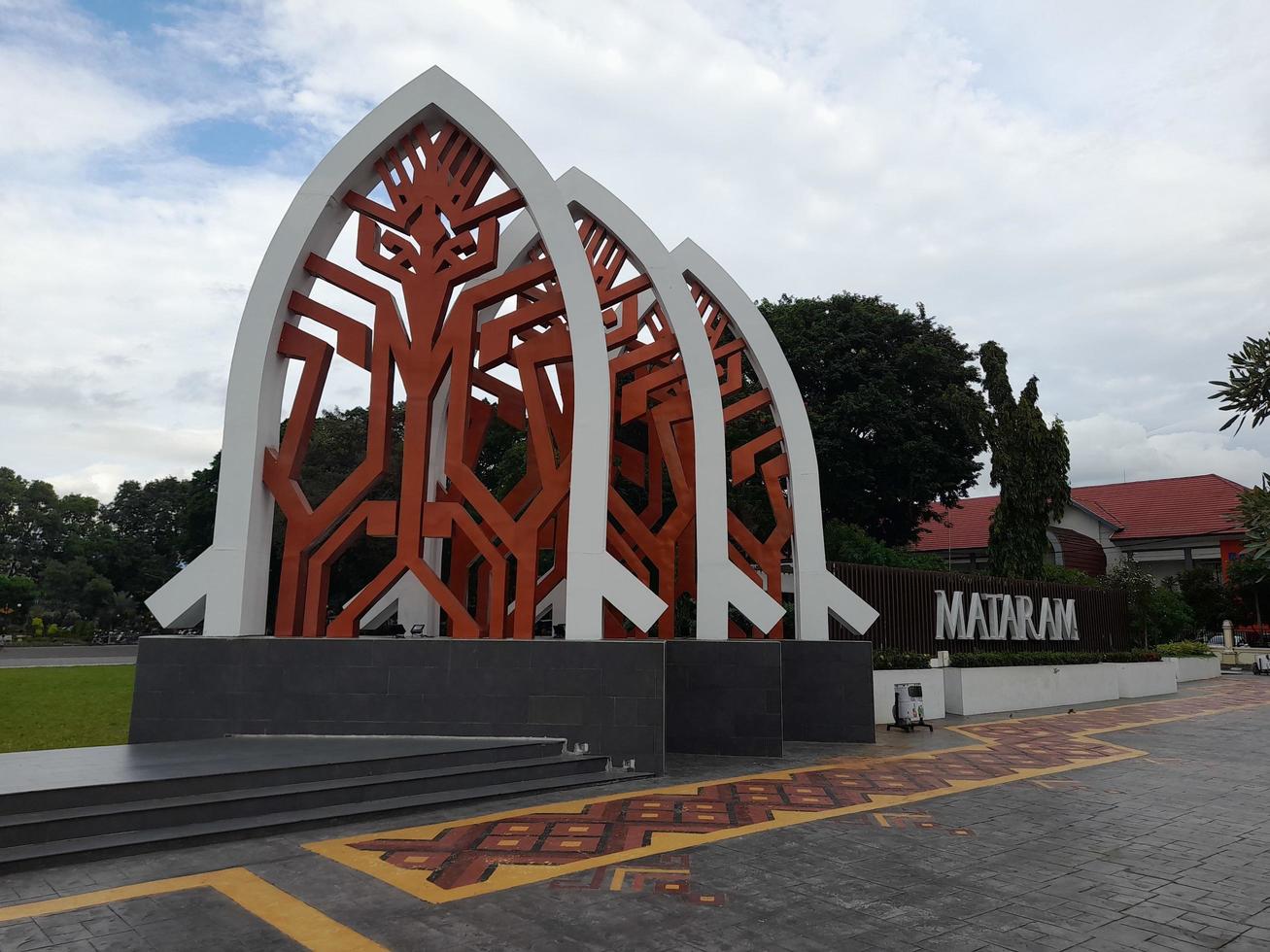 Mataram, Indonesia, February 16, 2023. A gate with the shape of a white traditional house roof and a red cloth motif in Sangkareang Park in the center of Mataram city photo