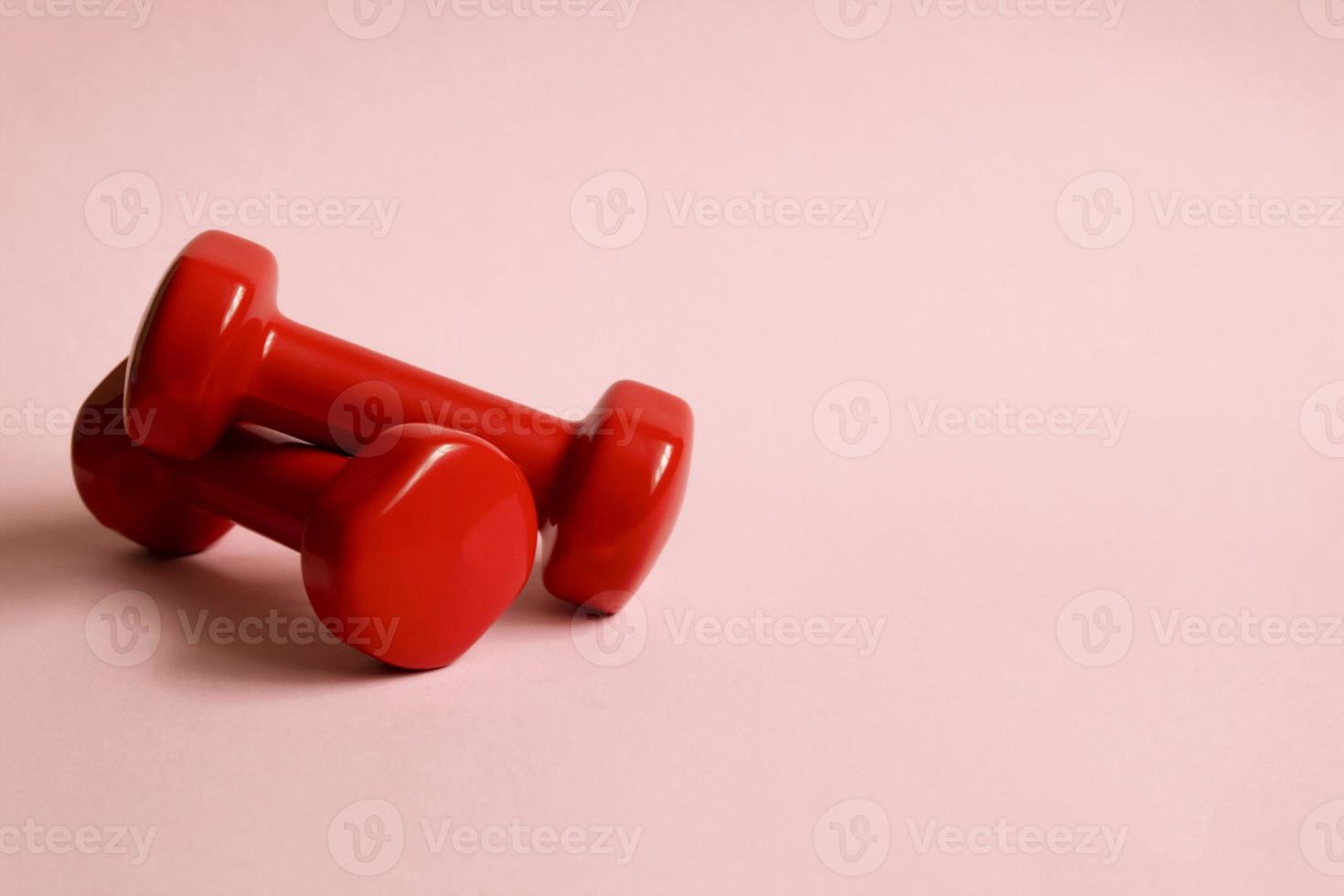 Two red dumbbells on a pink background. Sports equipment flat lay background photo