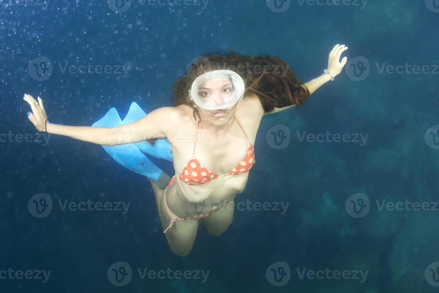 beautiful girl swimming under a boat and coming to you photo