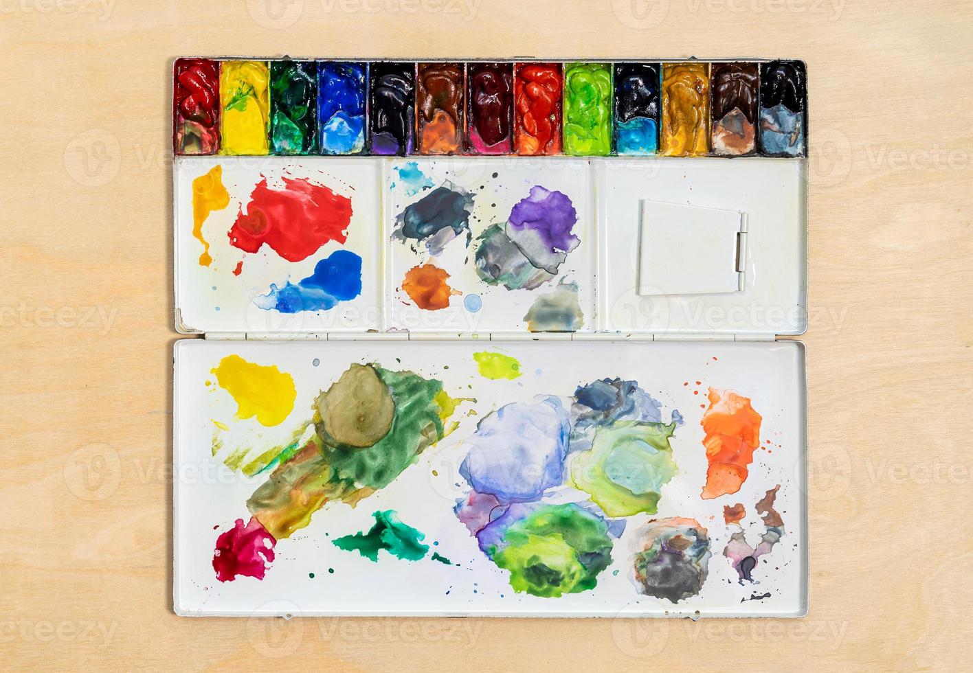 Metal watercolor palette box with colorful watercolor set on wood background. photo