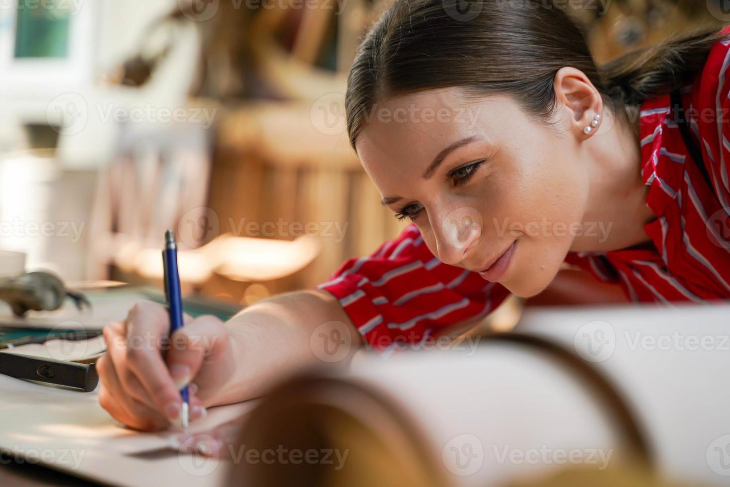 Closeup and crop young female leather goods maker is drawing a design