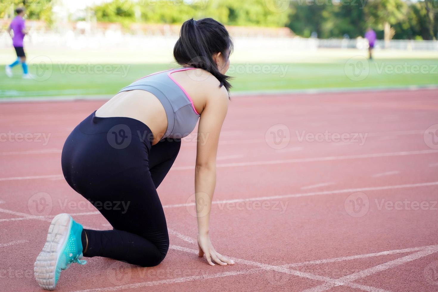 Back view of young female acting ready to run at the football stadium in the morning and blurred background. photo