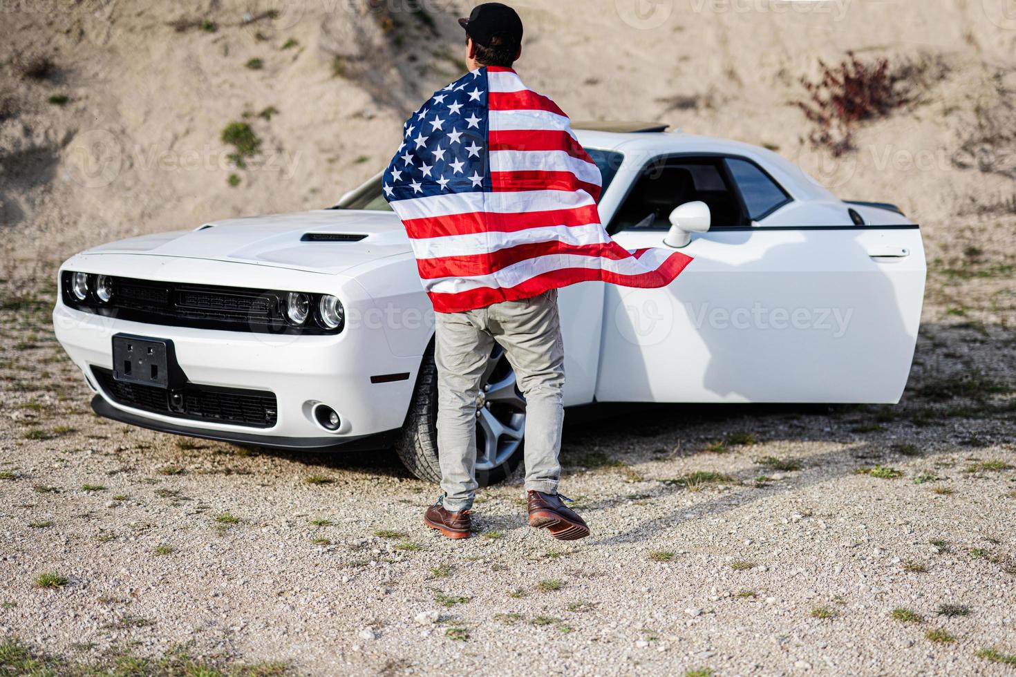 Back of man with USA flag near his white american muscle car in career. photo