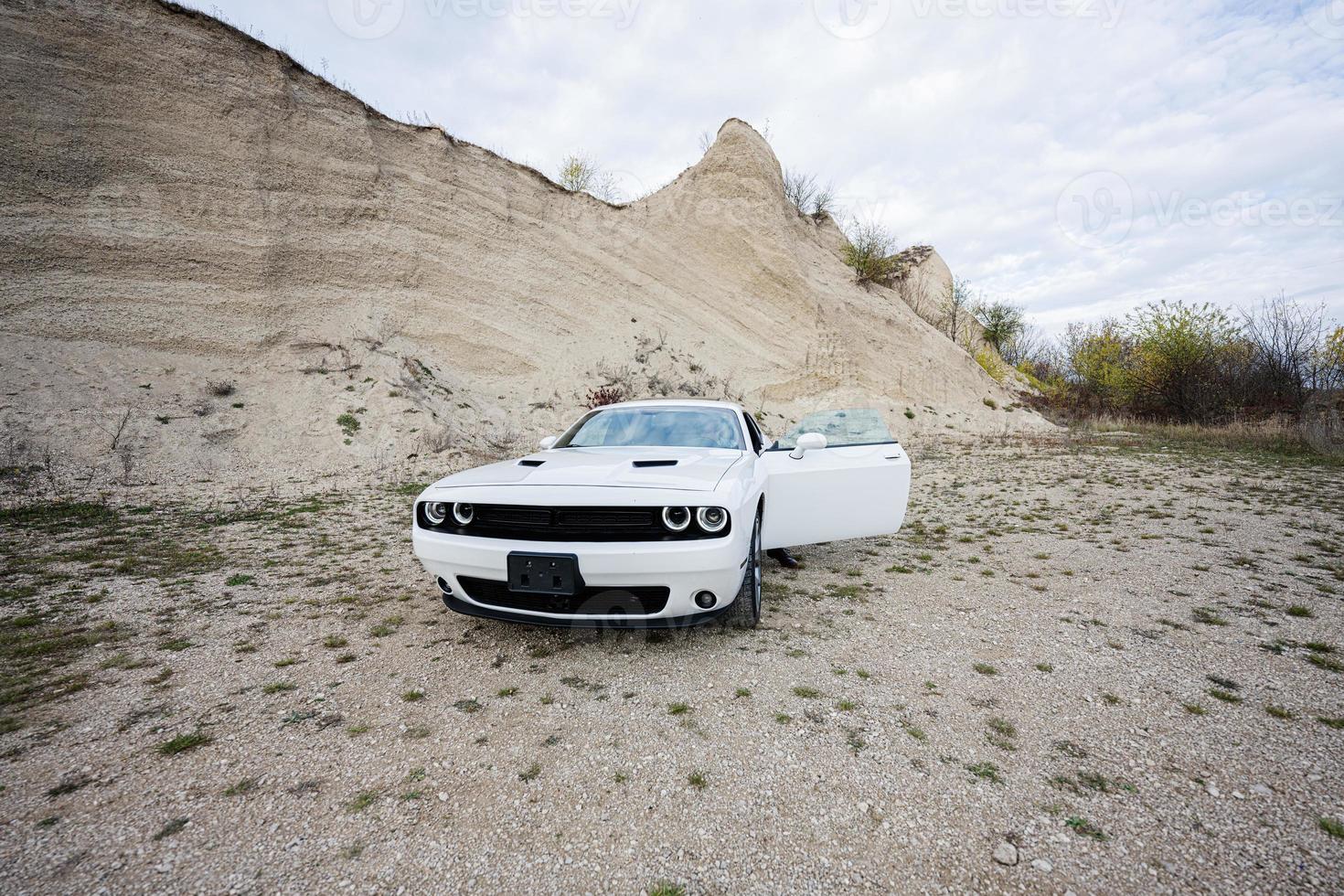 Handsome man sit in his white muscle car in career. photo